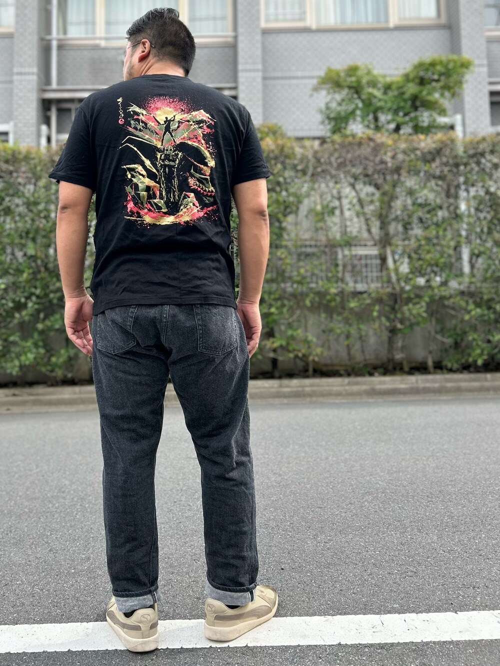 ブラック系のTシャツ/カットソー、ブラック系のデニムパンツ、ホワイト系のスニーカーを着用したメンズの夏コーディネートの2枚目の写真