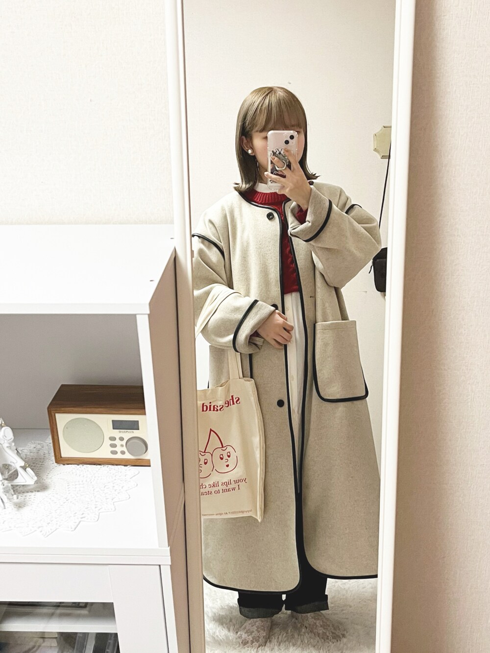 レッド系のニット/セーター、ホワイト系のシャツ/ブラウス、ベージュ系のダウンジャケット/コートを着用したレディースの冬コーディネートの2枚目の写真