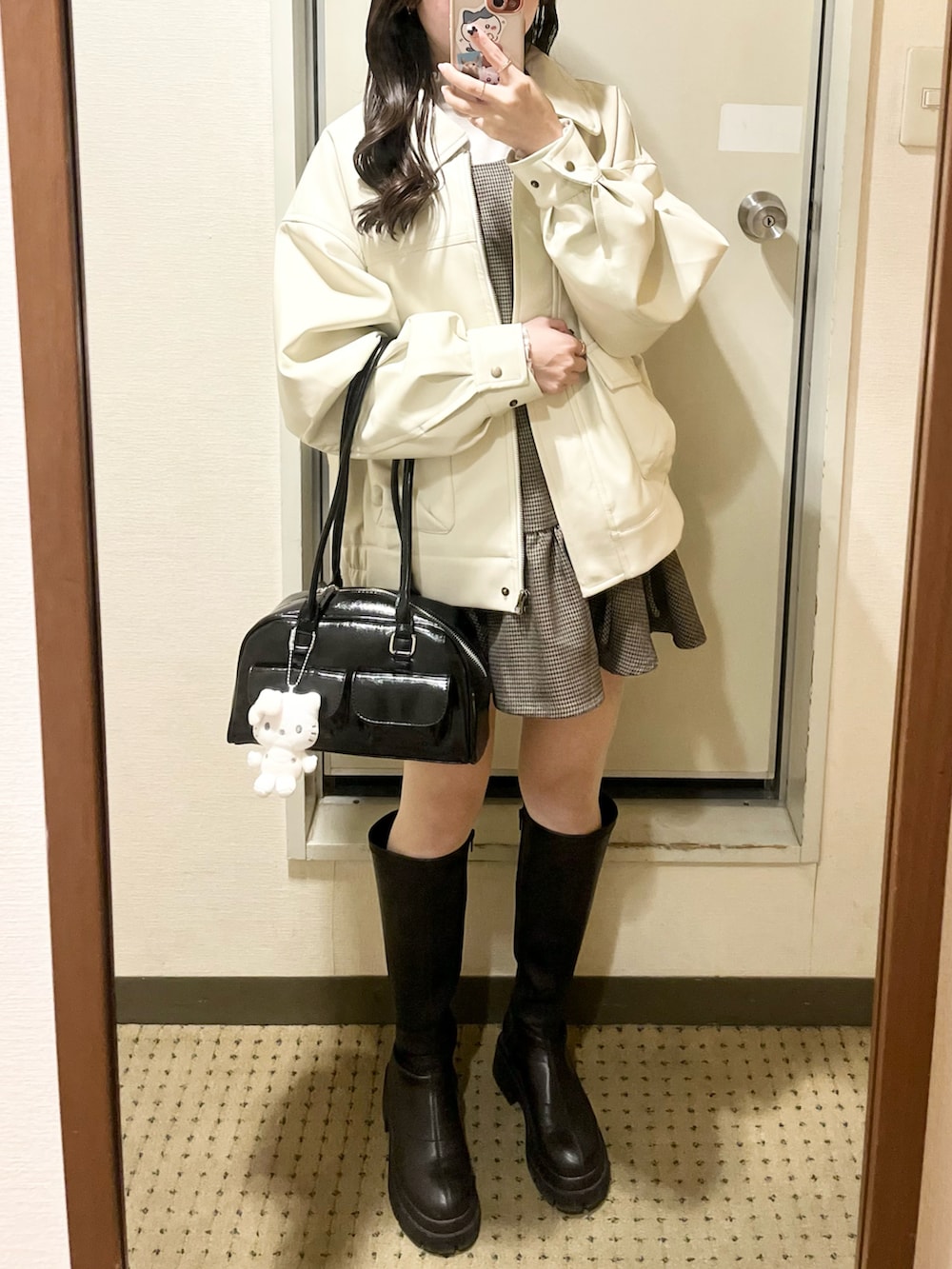 ブラウン系のジャンパースカート、ホワイト系のニット/セーター、ブラック系のブーツを着用したレディースの冬コーディネートの2枚目の写真