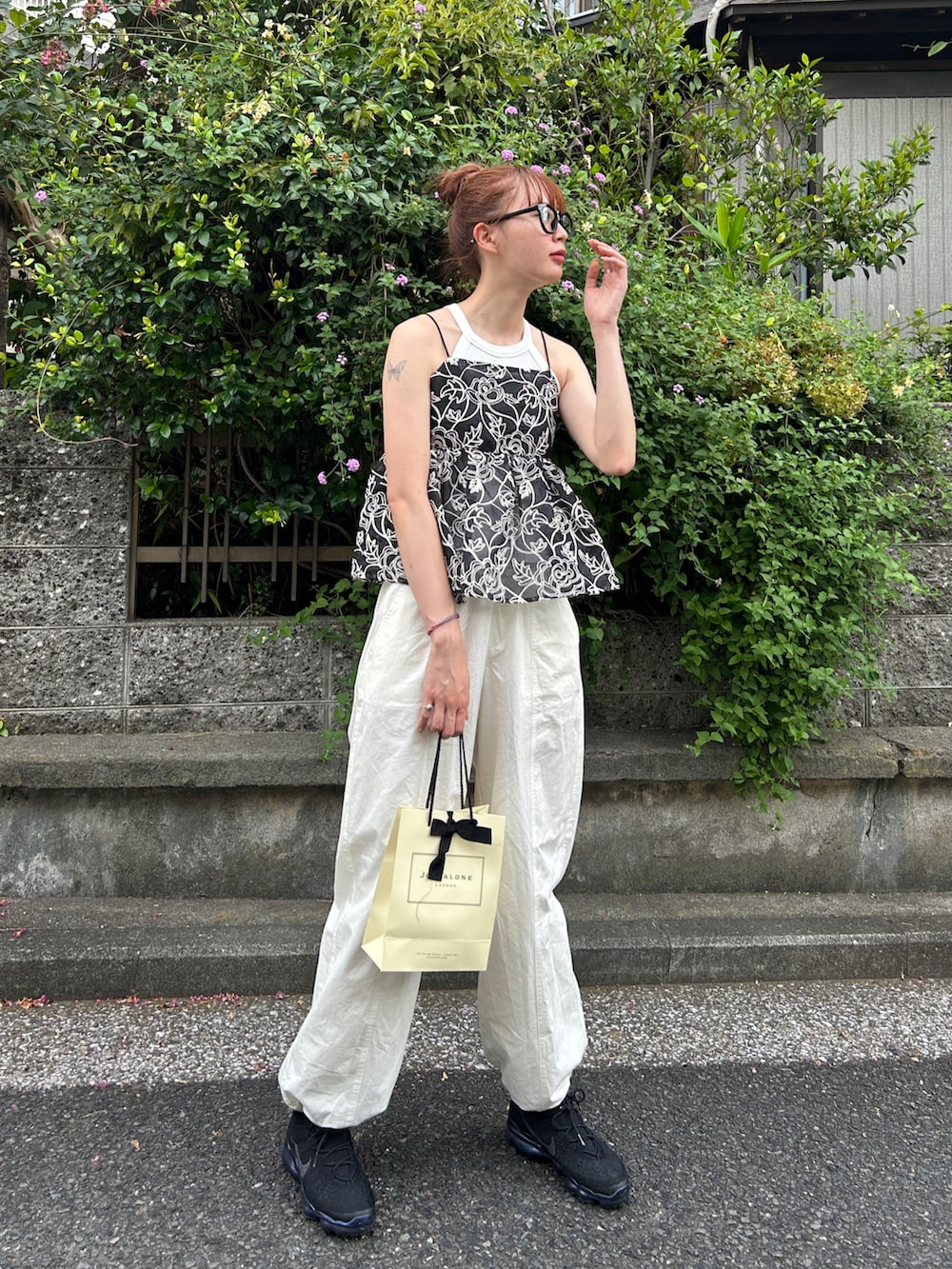 ブラック系のキャミソール、ホワイト系のパンツ、ブラック系のスニーカーを着用したレディースの夏コーディネートの2枚目の写真