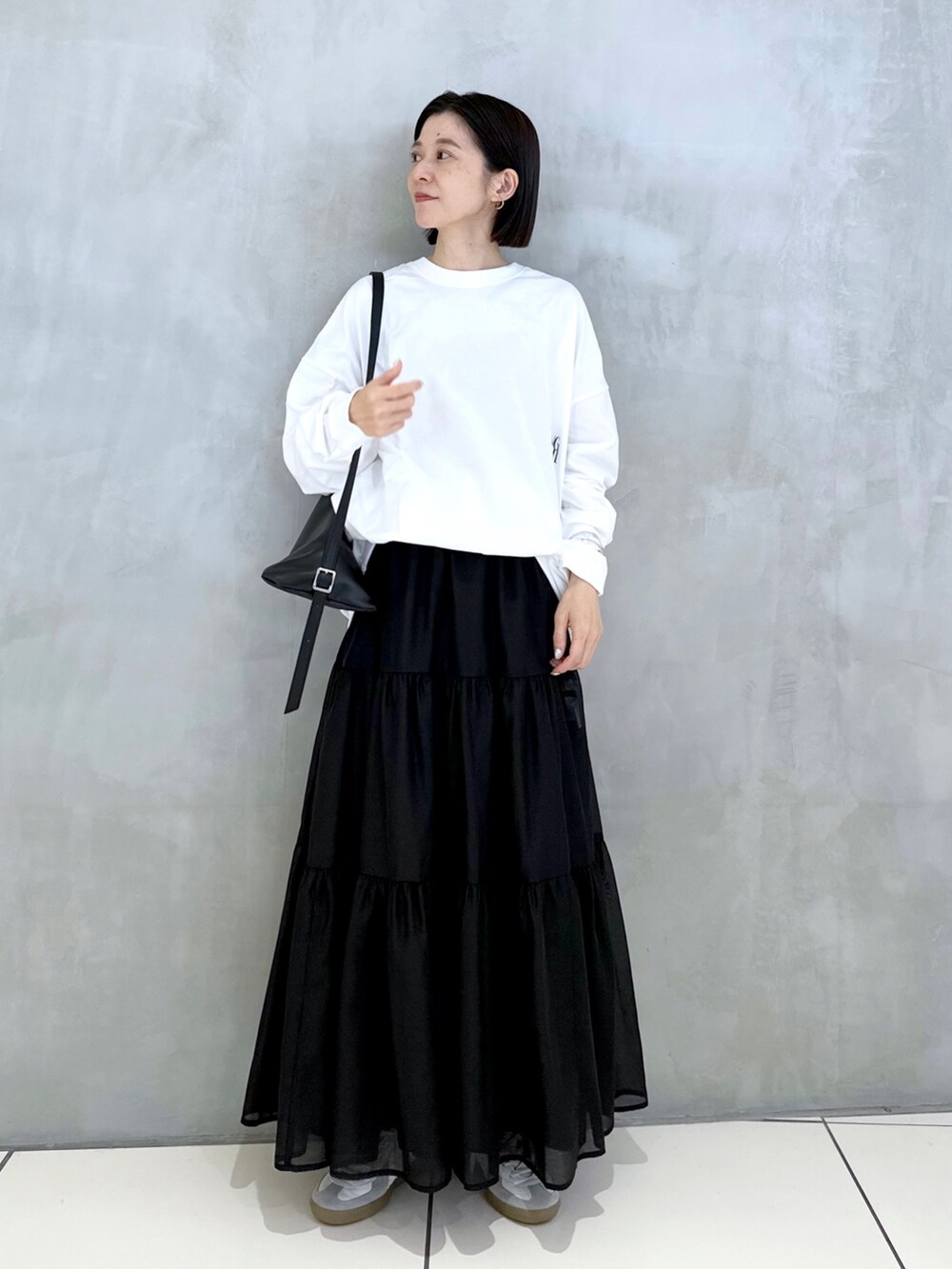 ブラック系のショルダーバッグ、ホワイト系のTシャツ/カットソー、ブラック系のスカートを着用したレディースの秋コーディネートの3枚目の写真