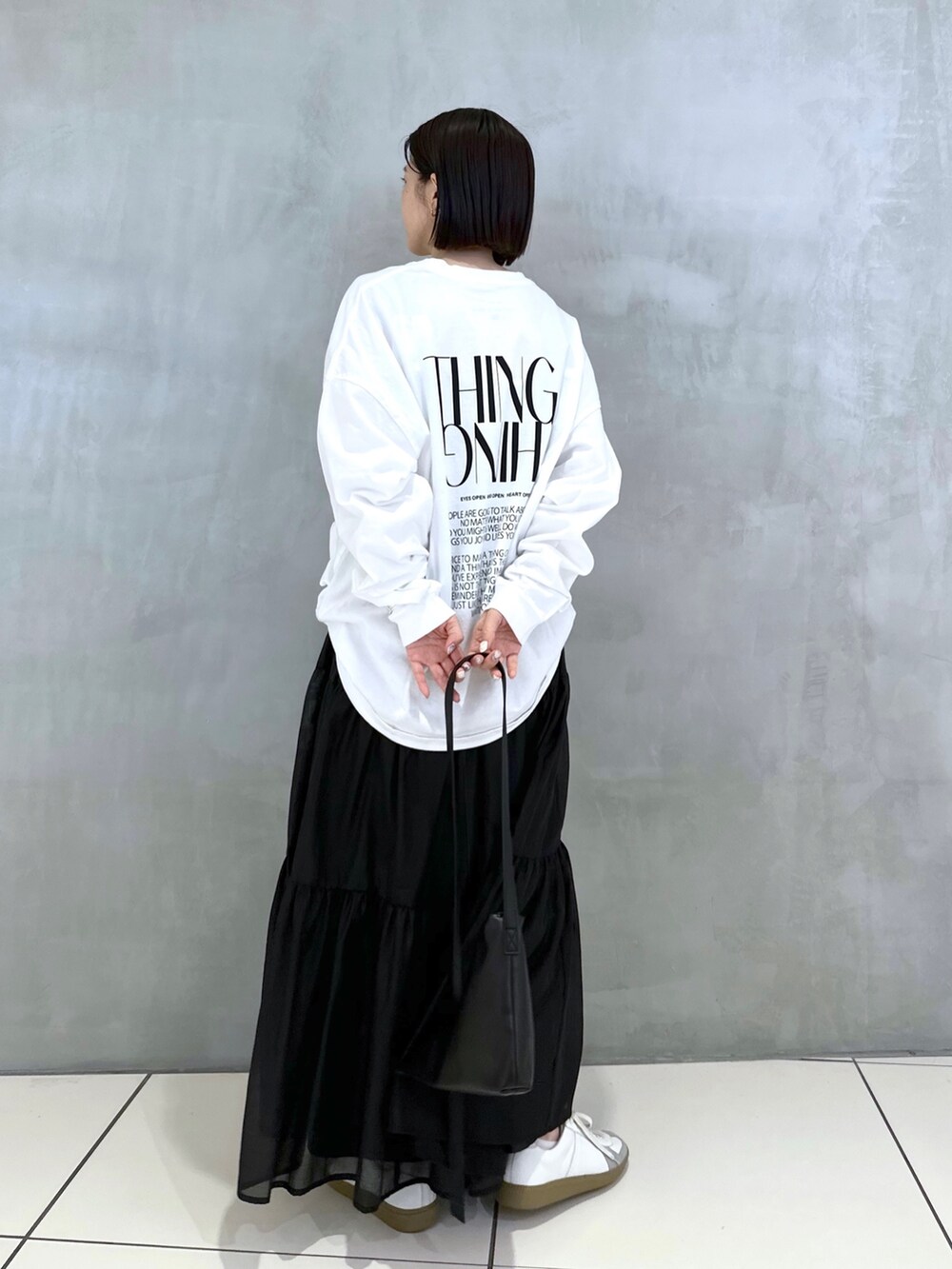 ブラック系のショルダーバッグ、ホワイト系のTシャツ/カットソー、ブラック系のスカートを着用したレディースの秋コーディネートの4枚目の写真