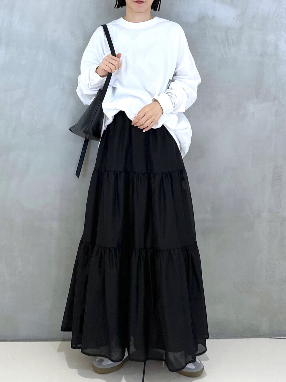 ブラック系のショルダーバッグ、ホワイト系のTシャツ/カットソー、ブラック系のスカートを着用したレディースの秋コーディネートの2枚目の写真