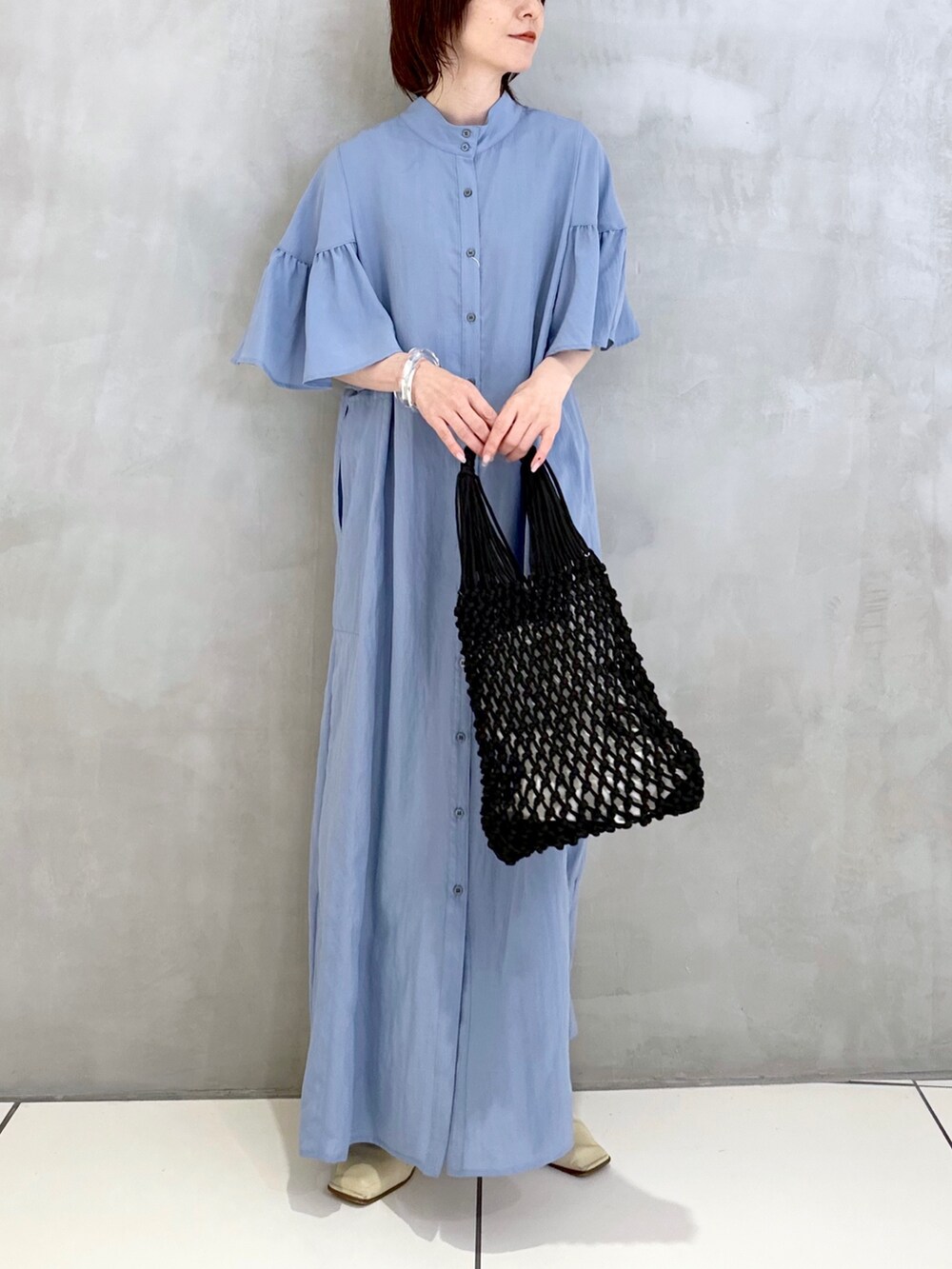 ブルー系のワンピース、ブラック系のハンドバッグを着用したレディースの夏コーディネートの2枚目の写真