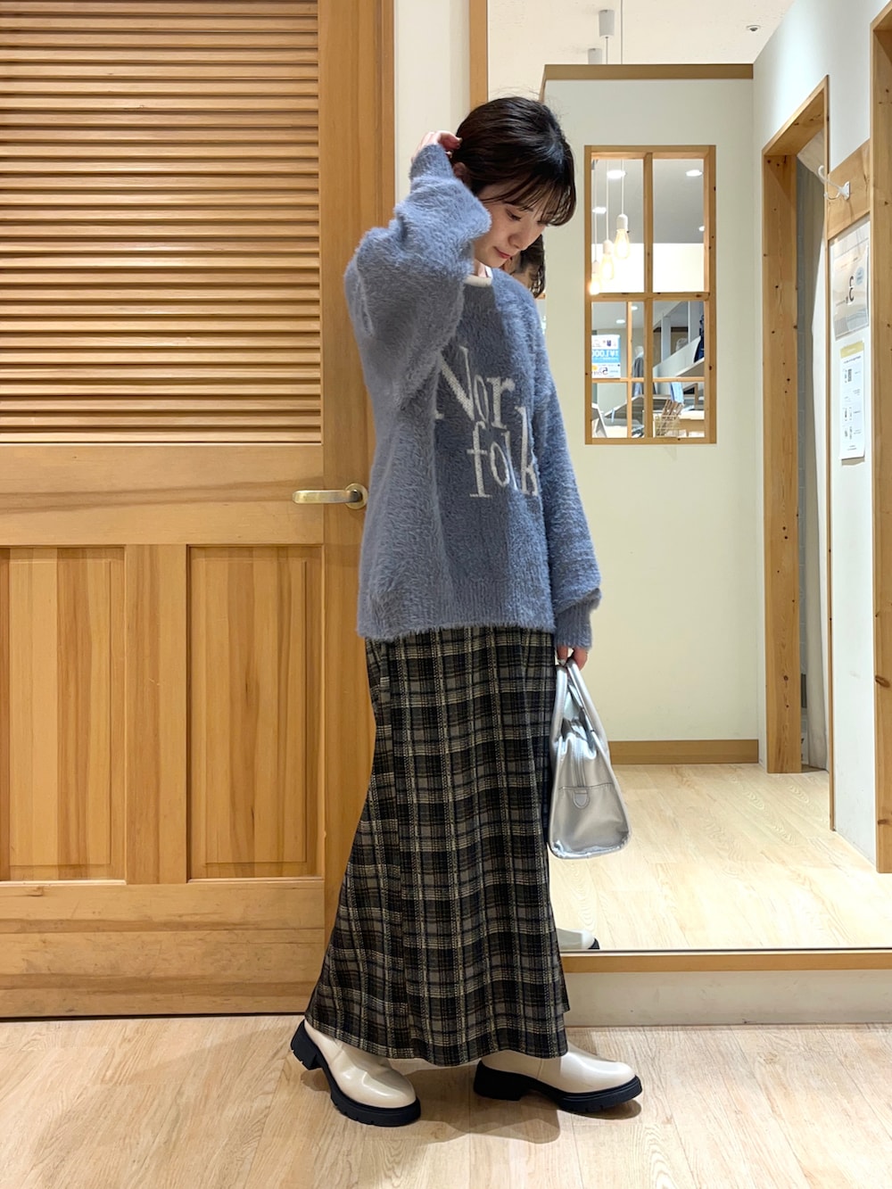 ベージュ系のブーツ、ブラック系のスカート、シルバー系のハンドバッグを着用したレディースの秋コーディネートの4枚目の写真