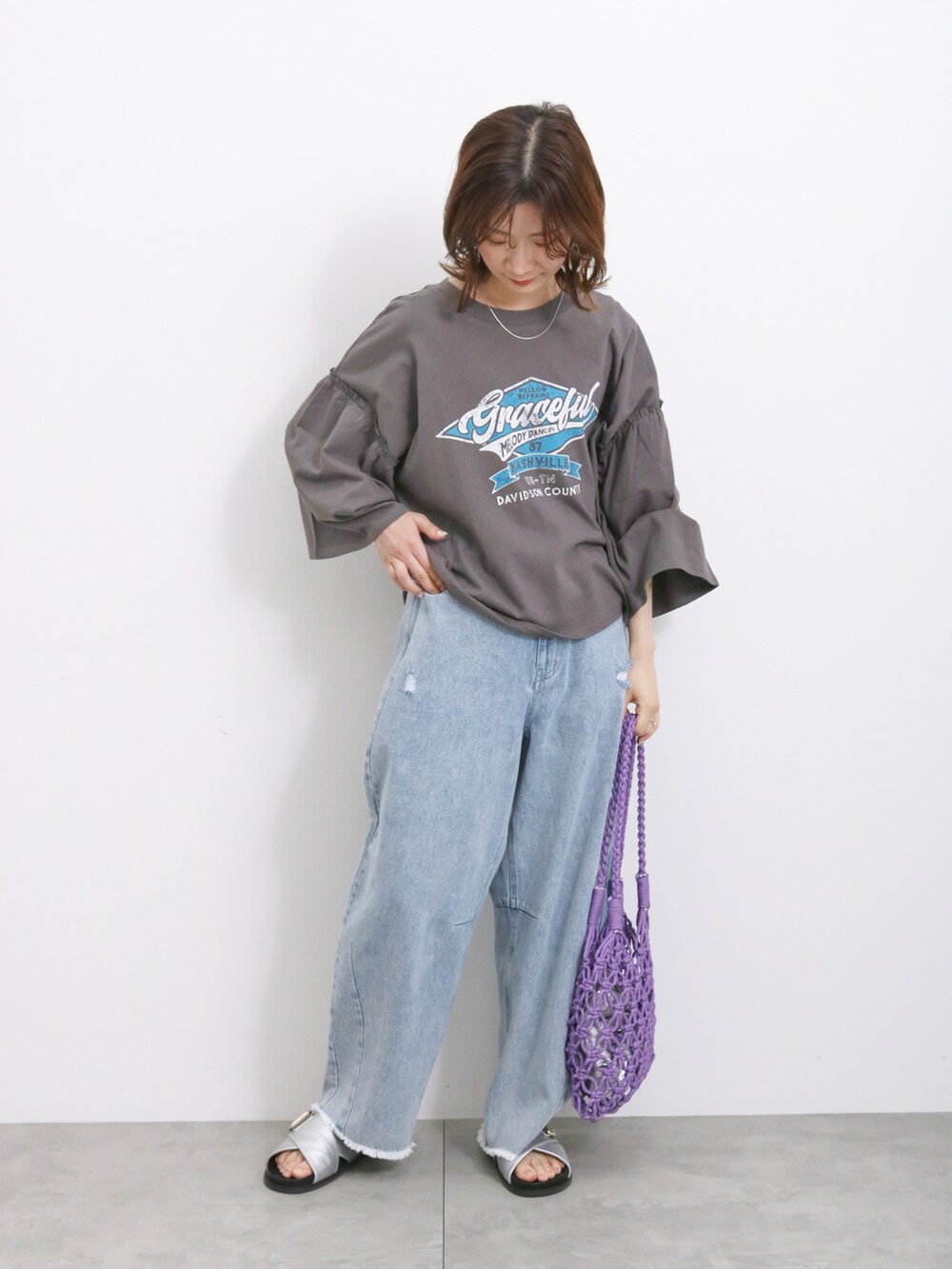 ブルー系のデニムパンツ、パープル系のハンドバッグ、シルバー系のドレスシューズを着用したレディースの夏コーディネートの2枚目の写真