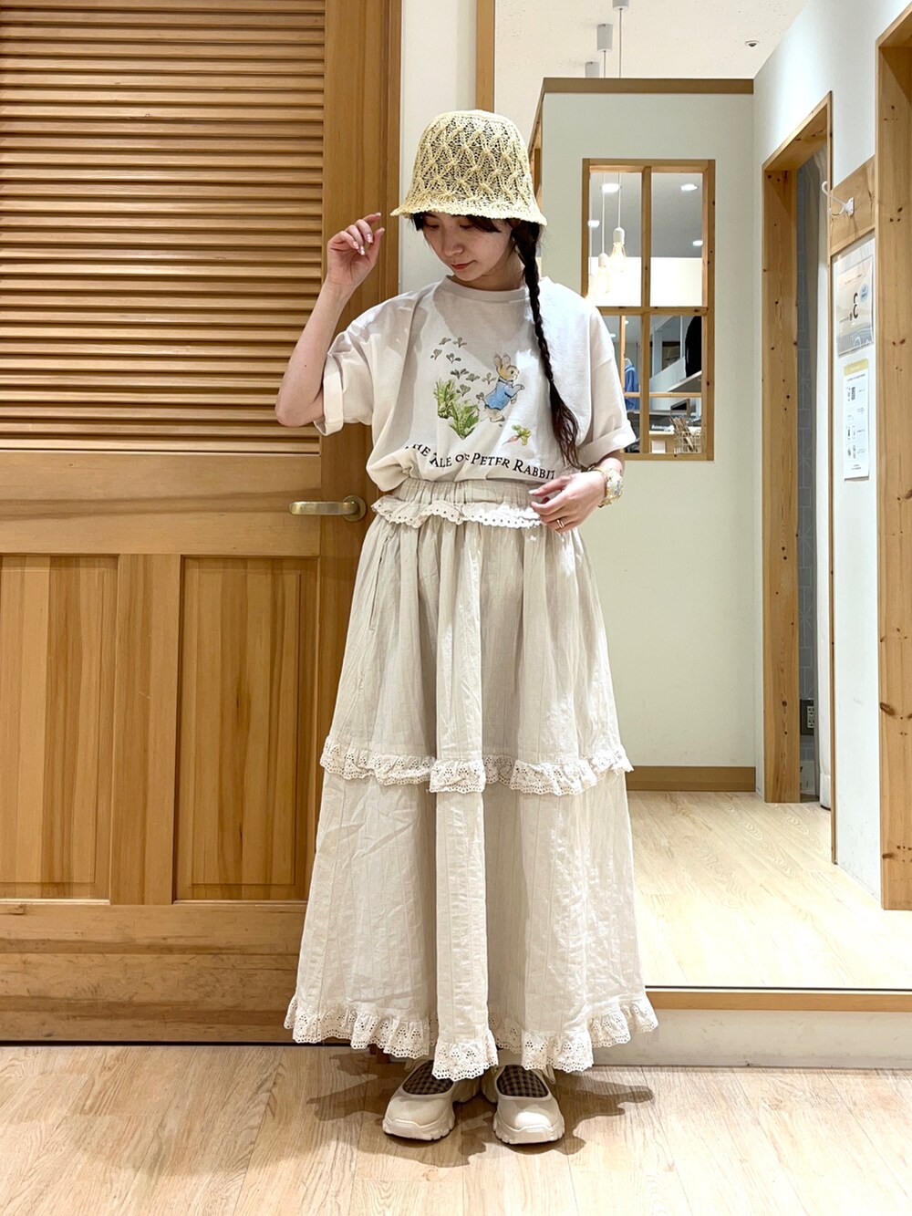 ホワイト系のTシャツ/カットソー、ベージュ系のスカート、ベージュ系のスニーカーを着用したレディースの春コーディネートの2枚目の写真