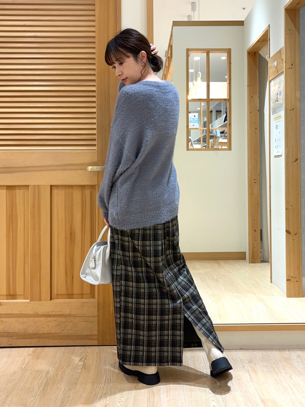 ベージュ系のブーツ、ブラック系のスカート、シルバー系のハンドバッグを着用したレディースの秋コーディネートの2枚目の写真