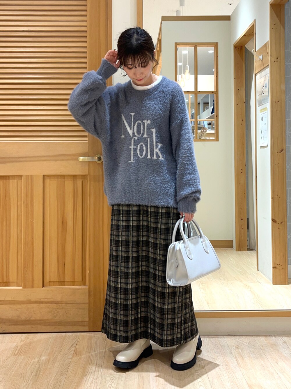 ベージュ系のブーツ、ブラック系のスカート、シルバー系のハンドバッグを着用したレディースの秋コーディネートの3枚目の写真