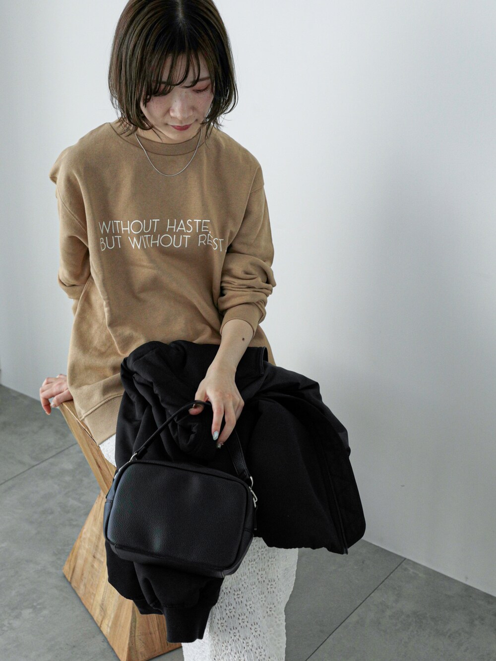 ブラック系のブルゾン、ベージュ系のTシャツ/カットソー、ホワイト系のスカートを着用したレディースの冬コーディネートの4枚目の写真