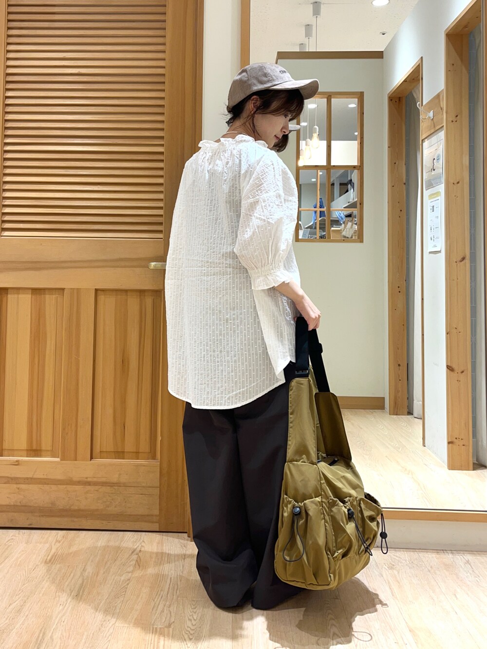 ホワイト系のシャツ/ブラウス、グレー系のその他パンツ、ベージュ系のハンドバッグを着用したレディースの夏コーディネートの3枚目の写真