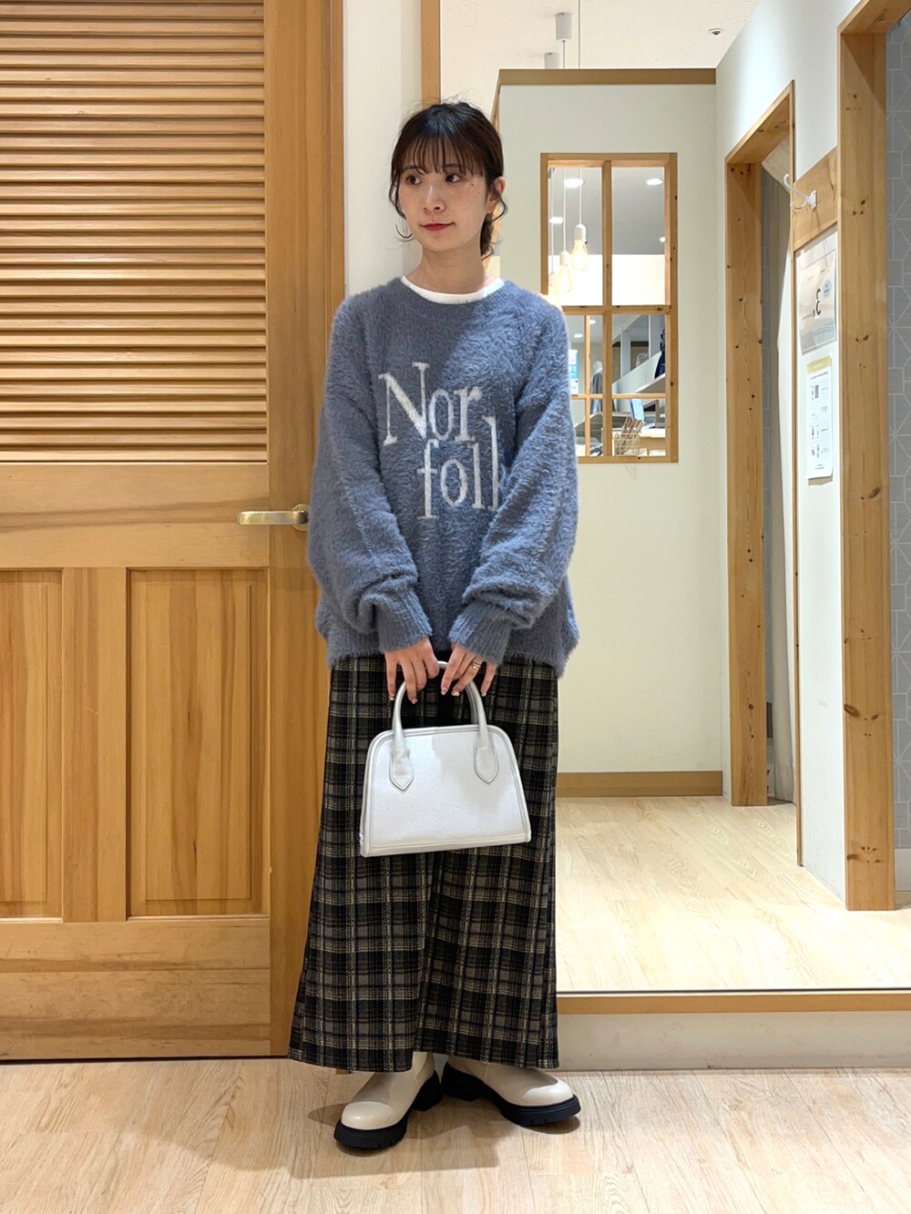 ベージュ系のブーツ、ブラック系のスカート、シルバー系のハンドバッグを着用したレディースの秋コーディネートの5枚目の写真