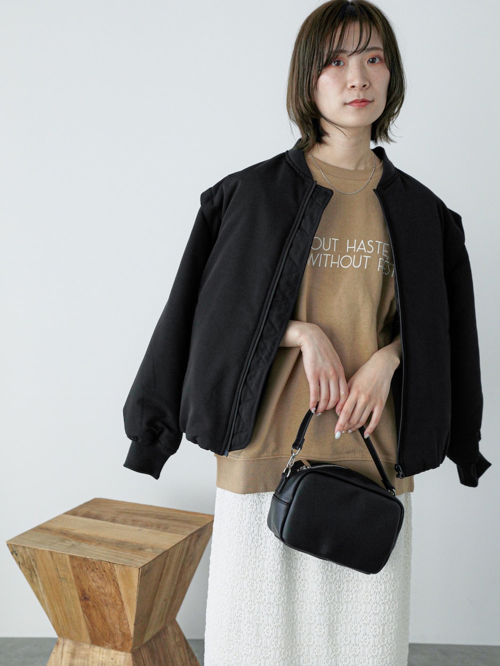 ブラック系のブルゾン、ベージュ系のTシャツ/カットソー、ホワイト系のスカートを着用したレディースの冬コーディネートの3枚目の写真