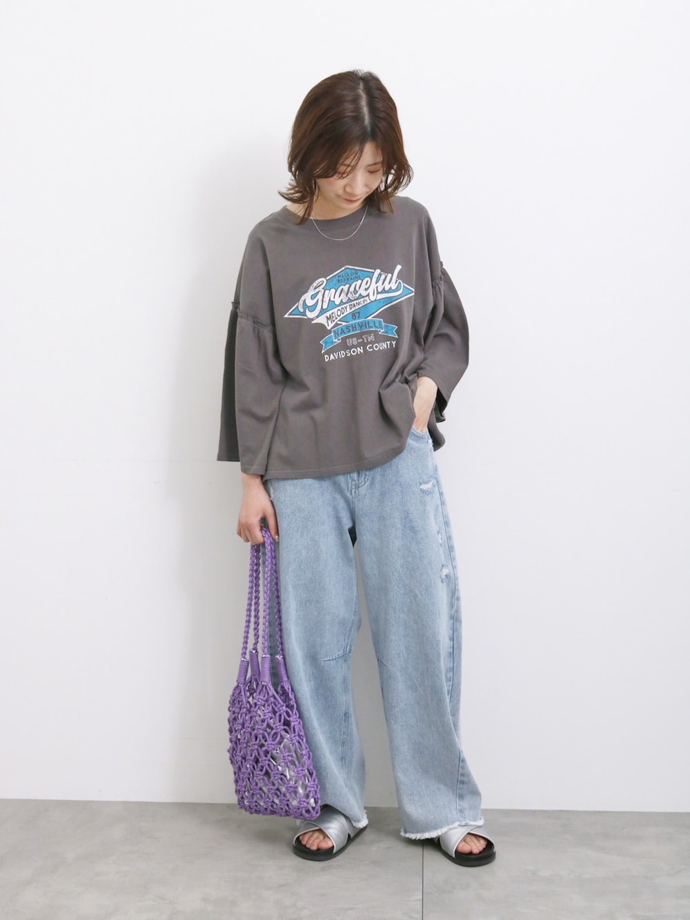 ブルー系のデニムパンツ、パープル系のハンドバッグ、シルバー系のドレスシューズを着用したレディースの夏コーディネートの3枚目の写真
