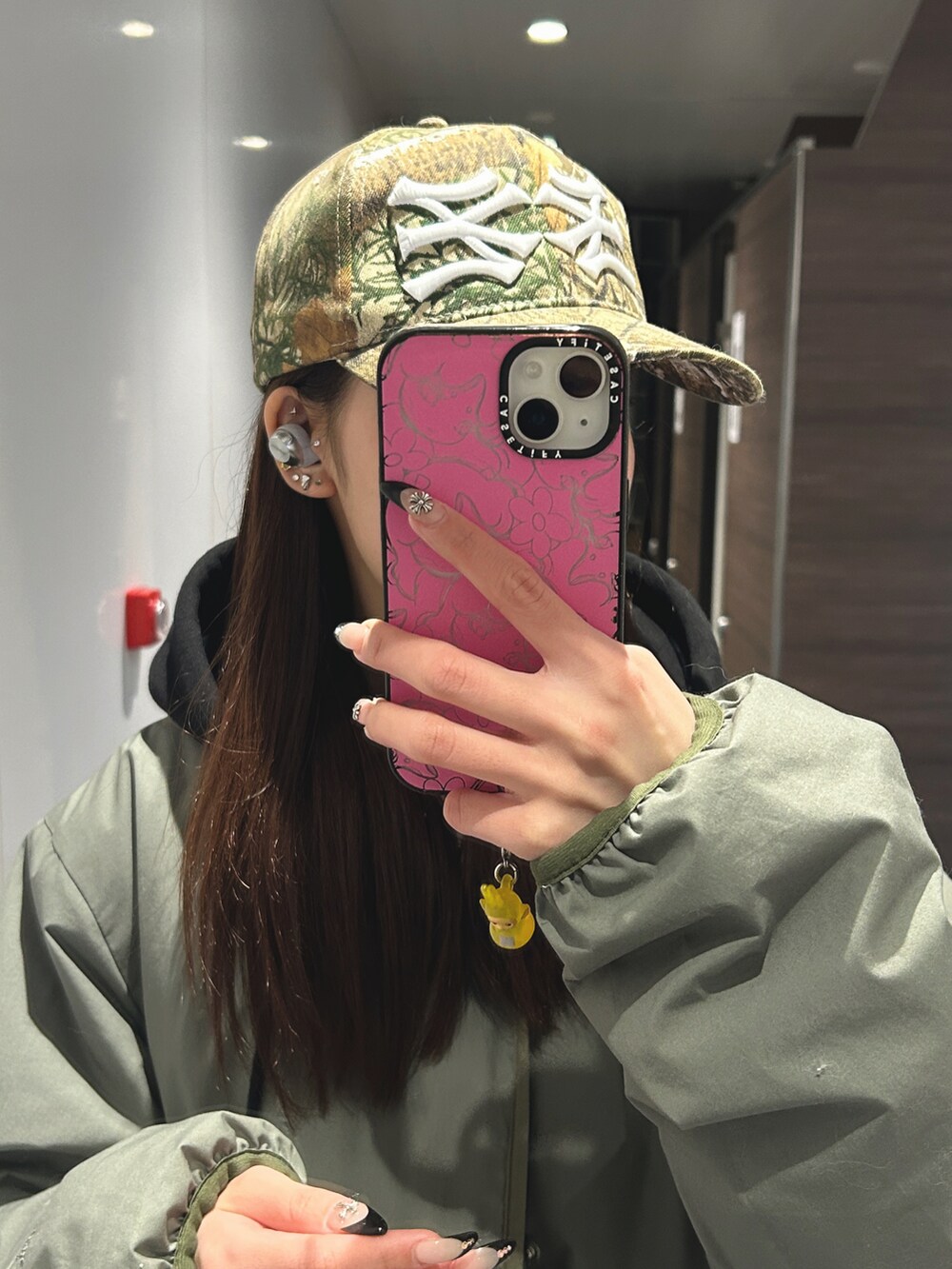 グリーン系のダウンジャケット/コート、ブラック系のハンドバッグ、ブルー系のデニムパンツを着用したレディースの春コーディネートの2枚目の写真