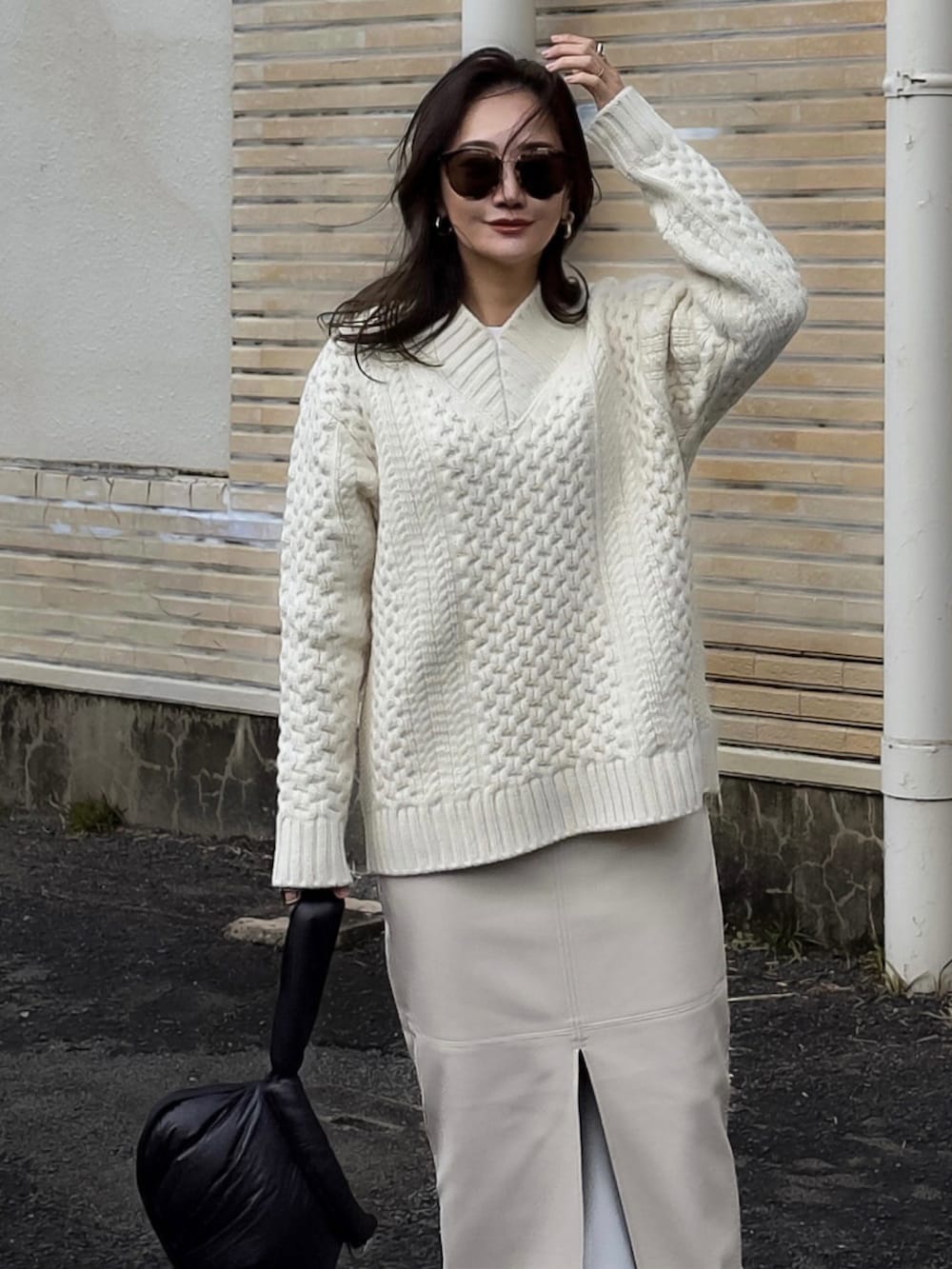 ホワイト系のニット/セーター、ホワイト系のスカート、ブラック系のブーツを着用したレディースの冬コーディネートの2枚目の写真