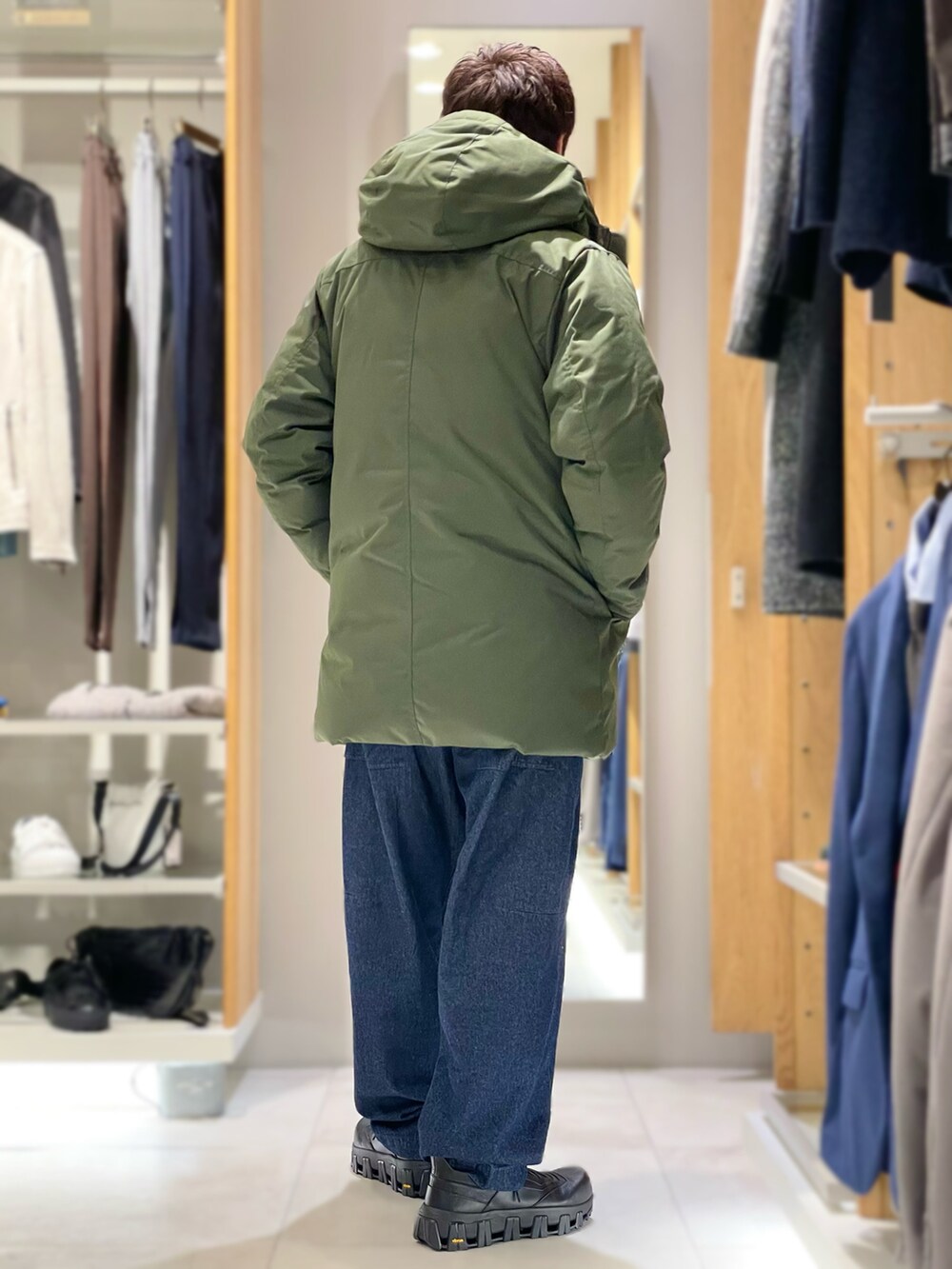 ブラック系のカーディガン/ボレロ、グリーン系のダウンジャケット/コート、ブルー系のデニムパンツを着用したメンズの秋コーディネートの3枚目の写真