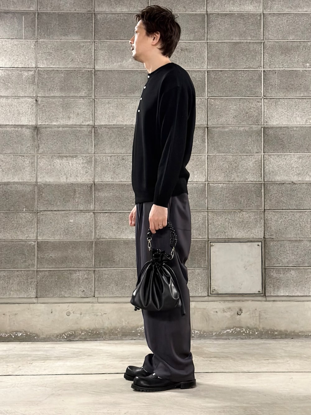 ブラック系のニット/セーター、ブルー系のスラックス、ブラック系のショルダーバッグを着用したメンズの冬コーディネートの2枚目の写真