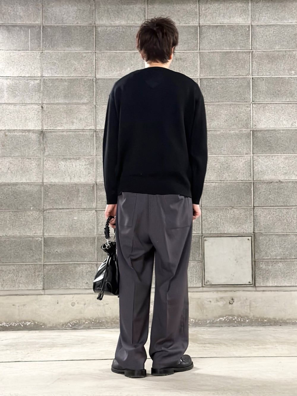 ブラック系のニット/セーター、ブルー系のスラックス、ブラック系のショルダーバッグを着用したメンズの冬コーディネートの3枚目の写真