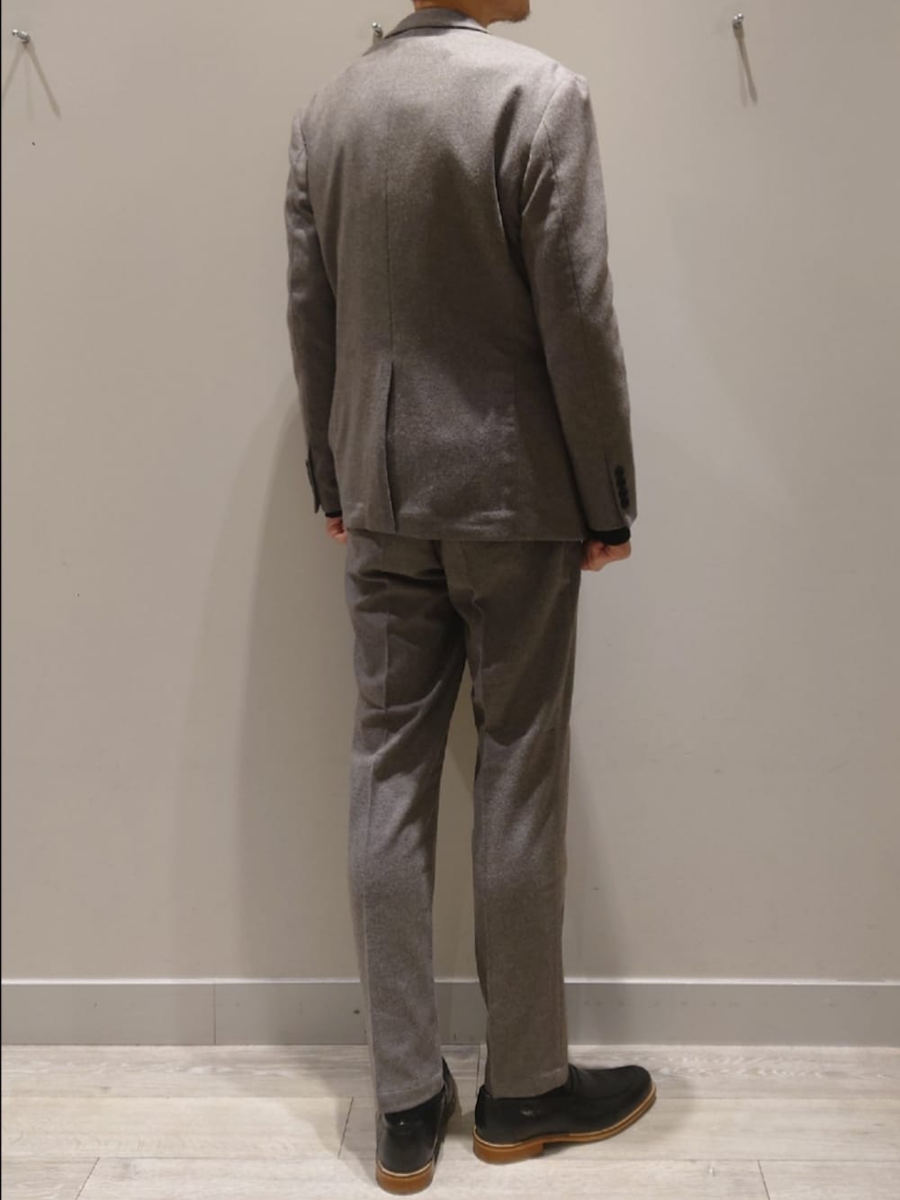 グレー系のテーラードジャケット、グレー系のスラックス、ブラック系のニット/セーターを着用したメンズの冬コーディネートの4枚目の写真