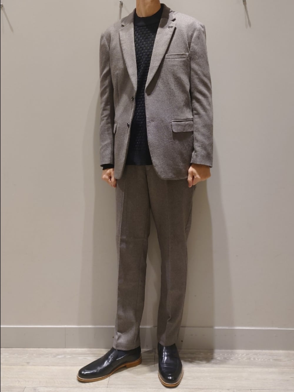 グレー系のテーラードジャケット、グレー系のスラックス、ブラック系のニット/セーターを着用したメンズの冬コーディネートの2枚目の写真