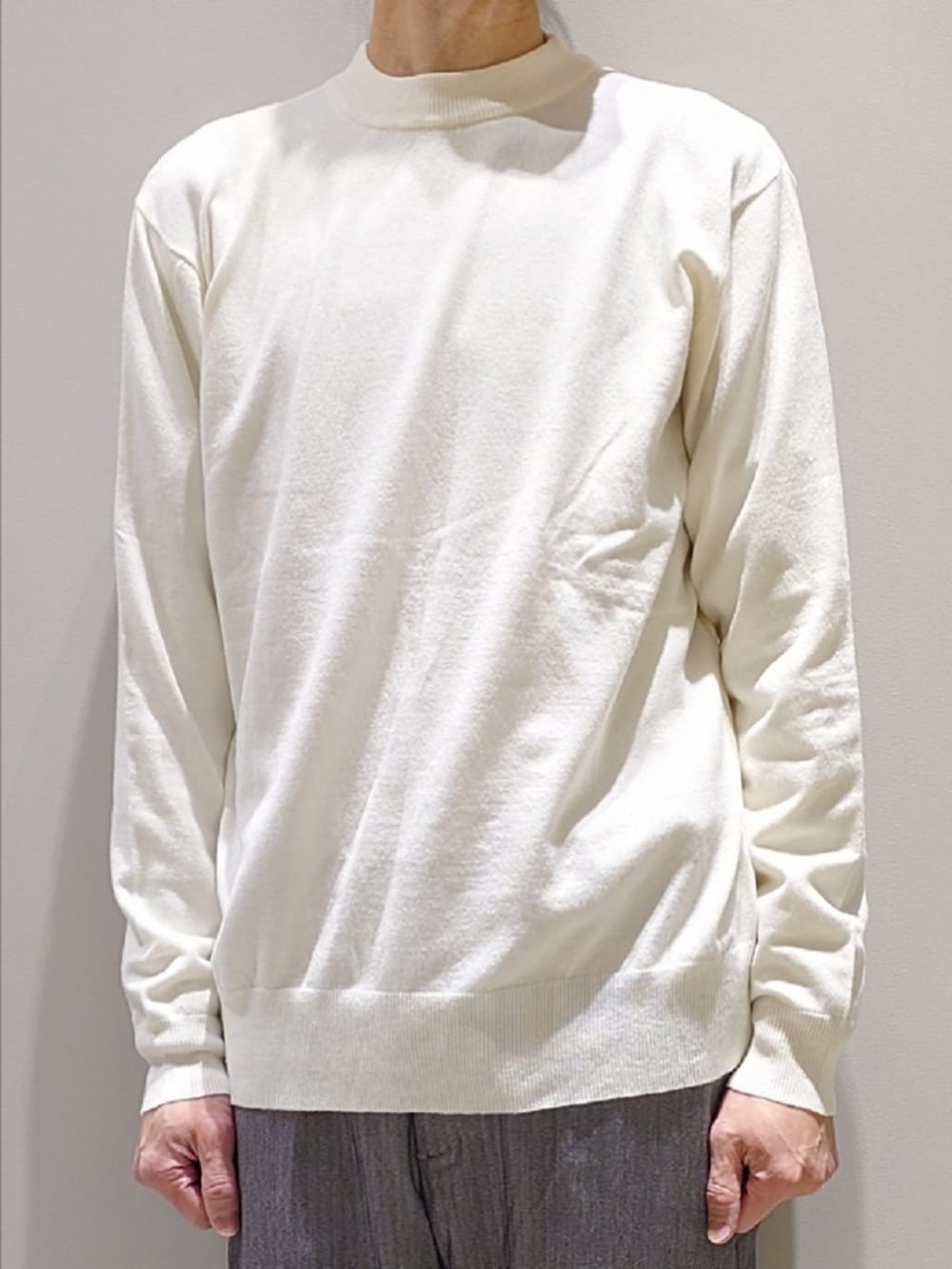 ホワイト系のニット/セーター、グレー系のスラックス、ブラック系のブーツを着用したメンズの冬コーディネートの5枚目の写真