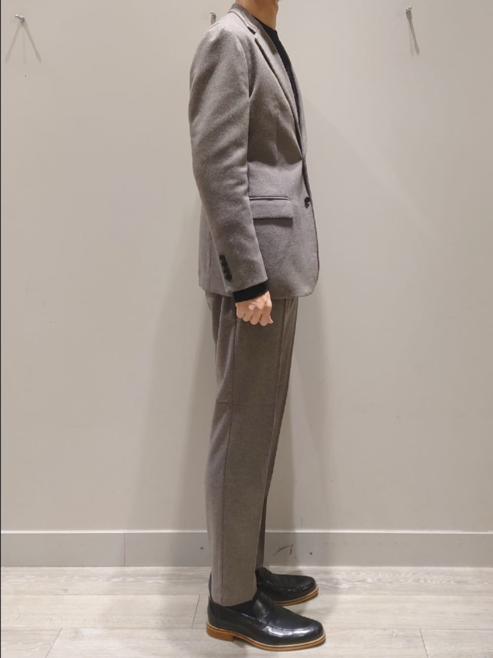 グレー系のテーラードジャケット、グレー系のスラックス、ブラック系のニット/セーターを着用したメンズの冬コーディネートの3枚目の写真