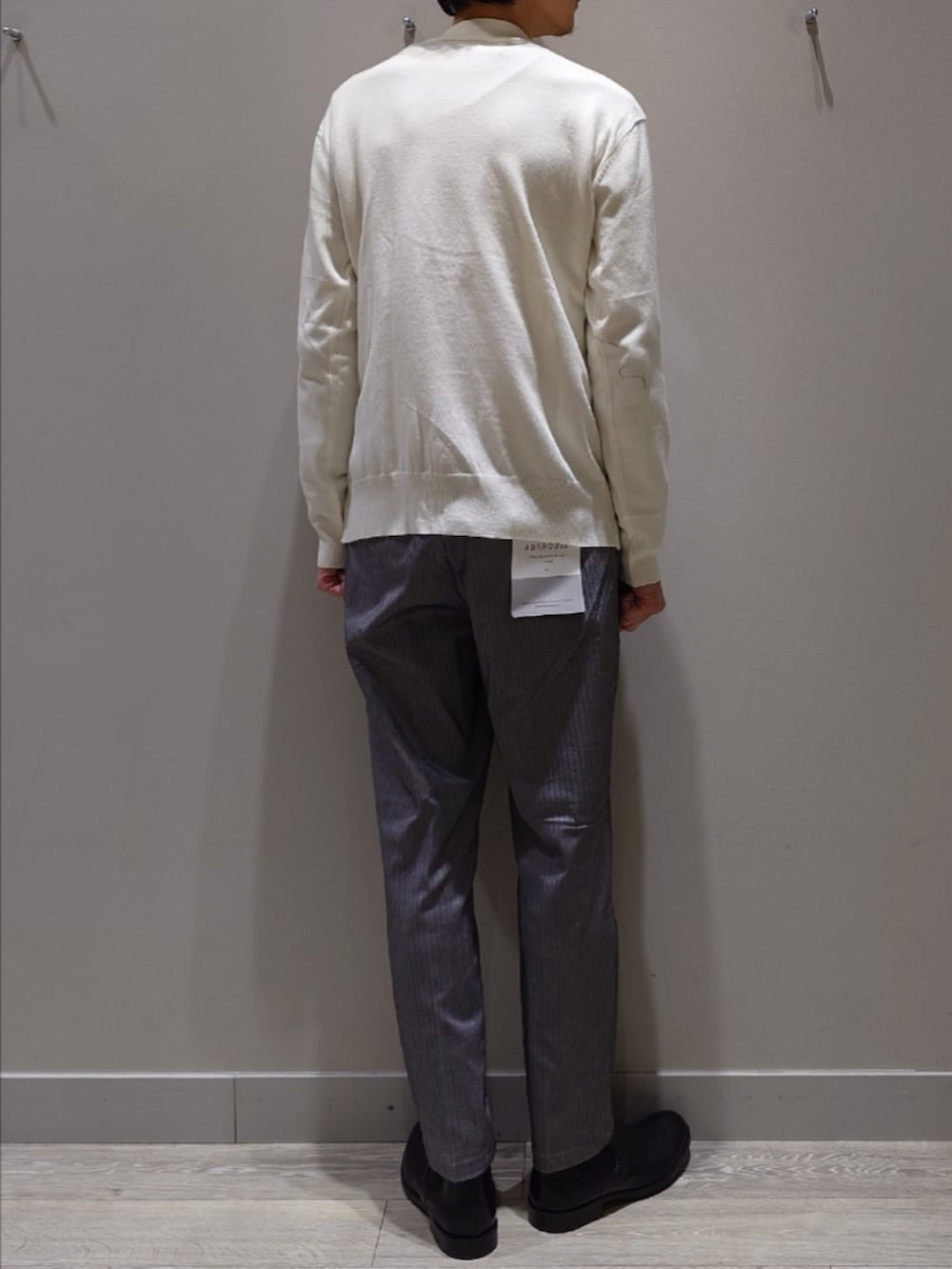 ホワイト系のニット/セーター、グレー系のスラックス、ブラック系のブーツを着用したメンズの冬コーディネートの4枚目の写真