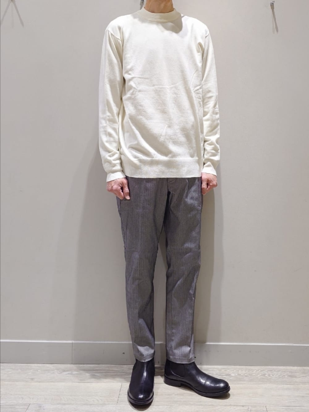 ホワイト系のニット/セーター、グレー系のスラックス、ブラック系のブーツを着用したメンズの冬コーディネートの2枚目の写真