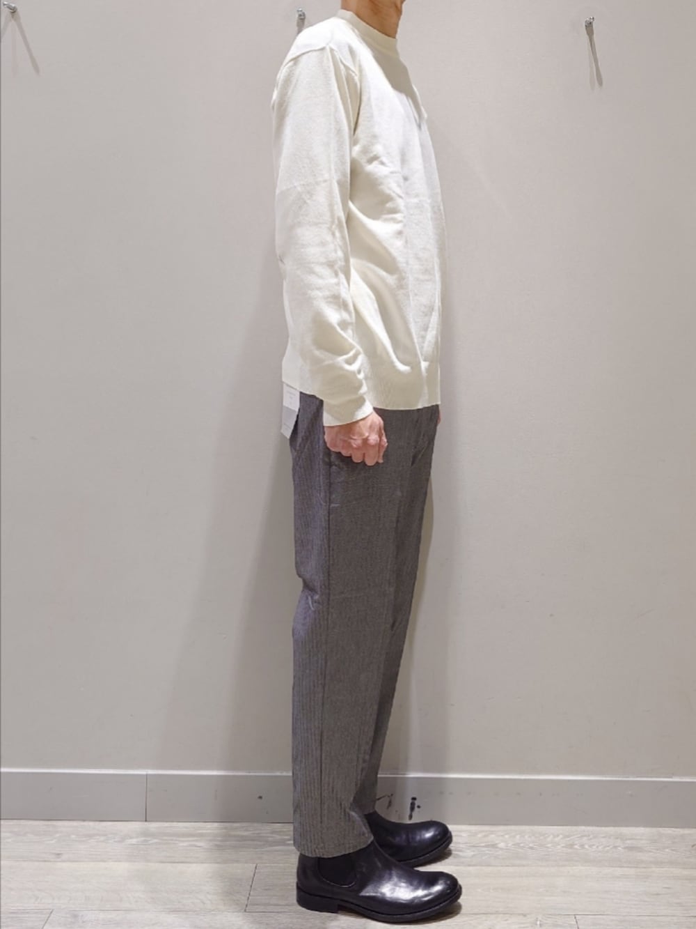 ホワイト系のニット/セーター、グレー系のスラックス、ブラック系のブーツを着用したメンズの冬コーディネートの3枚目の写真