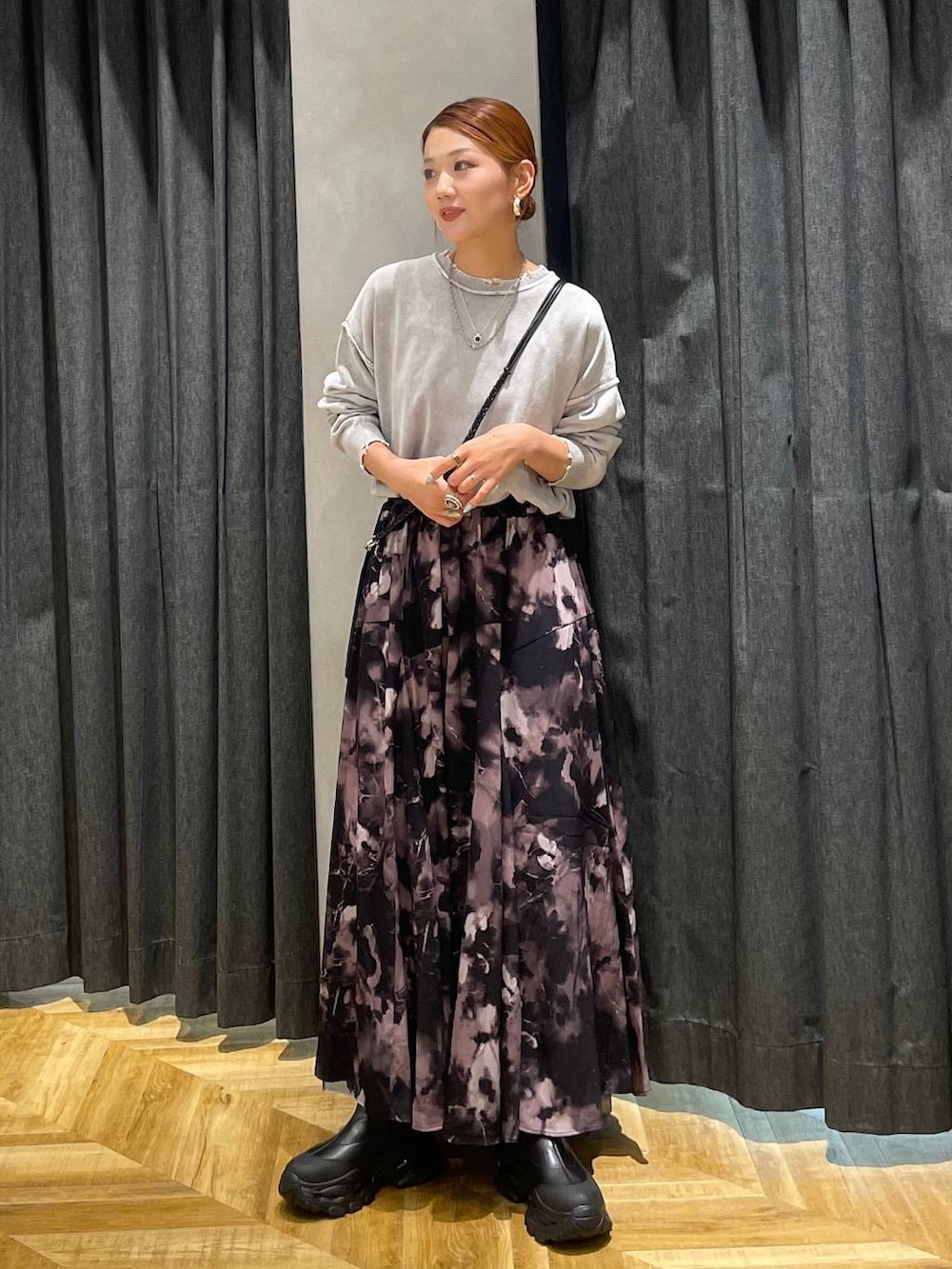 ブラック系のブーツ、グレー系のスカート、グレー系のニット/セーターを着用したレディースの秋コーディネートの2枚目の写真