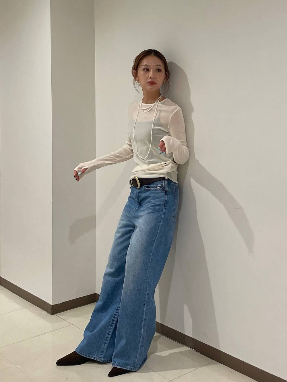 ホワイト系のTシャツ/カットソー、ブルー系のデニムパンツ、ブラック系のブーツを着用したレディースの秋コーディネートの2枚目の写真