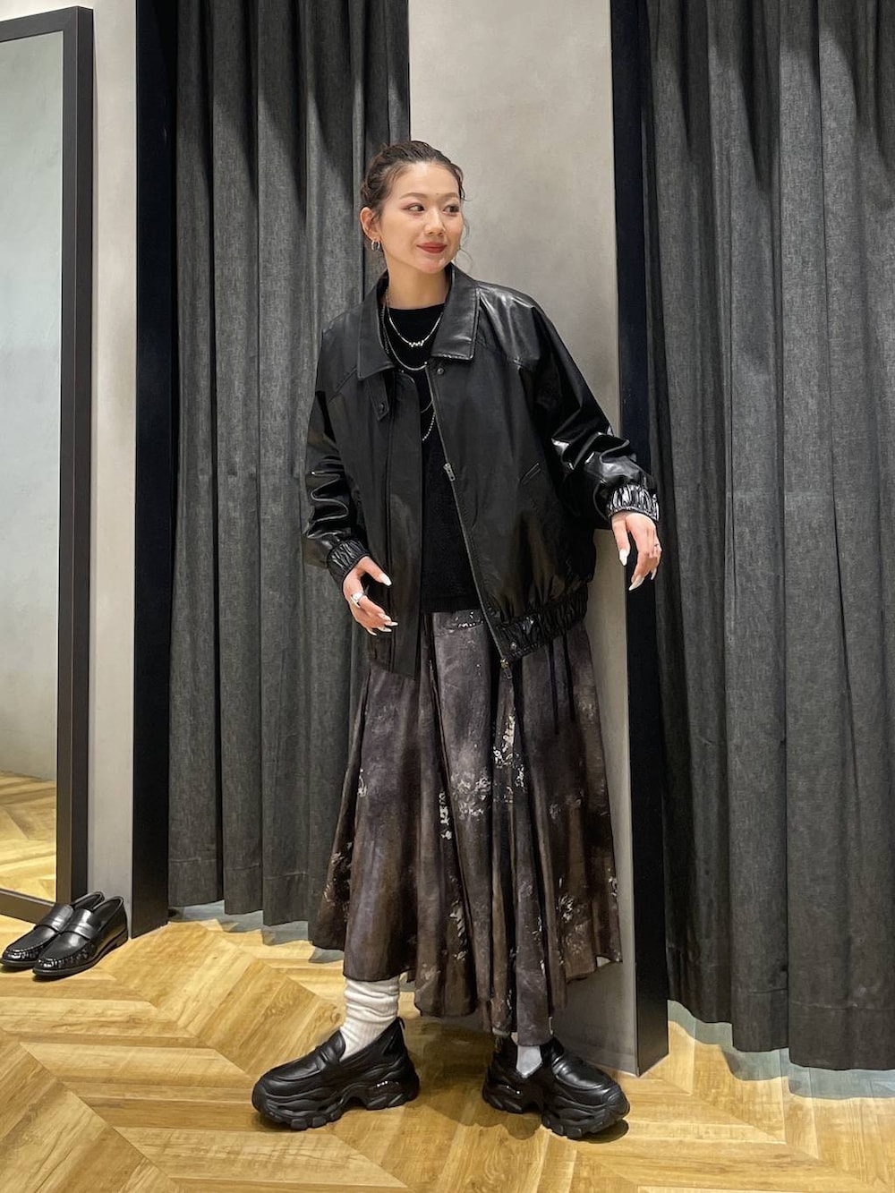 ブラック系のローファー、ブラック系のブルゾン、シルバー系のスカートを着用したレディースの冬コーディネートの2枚目の写真