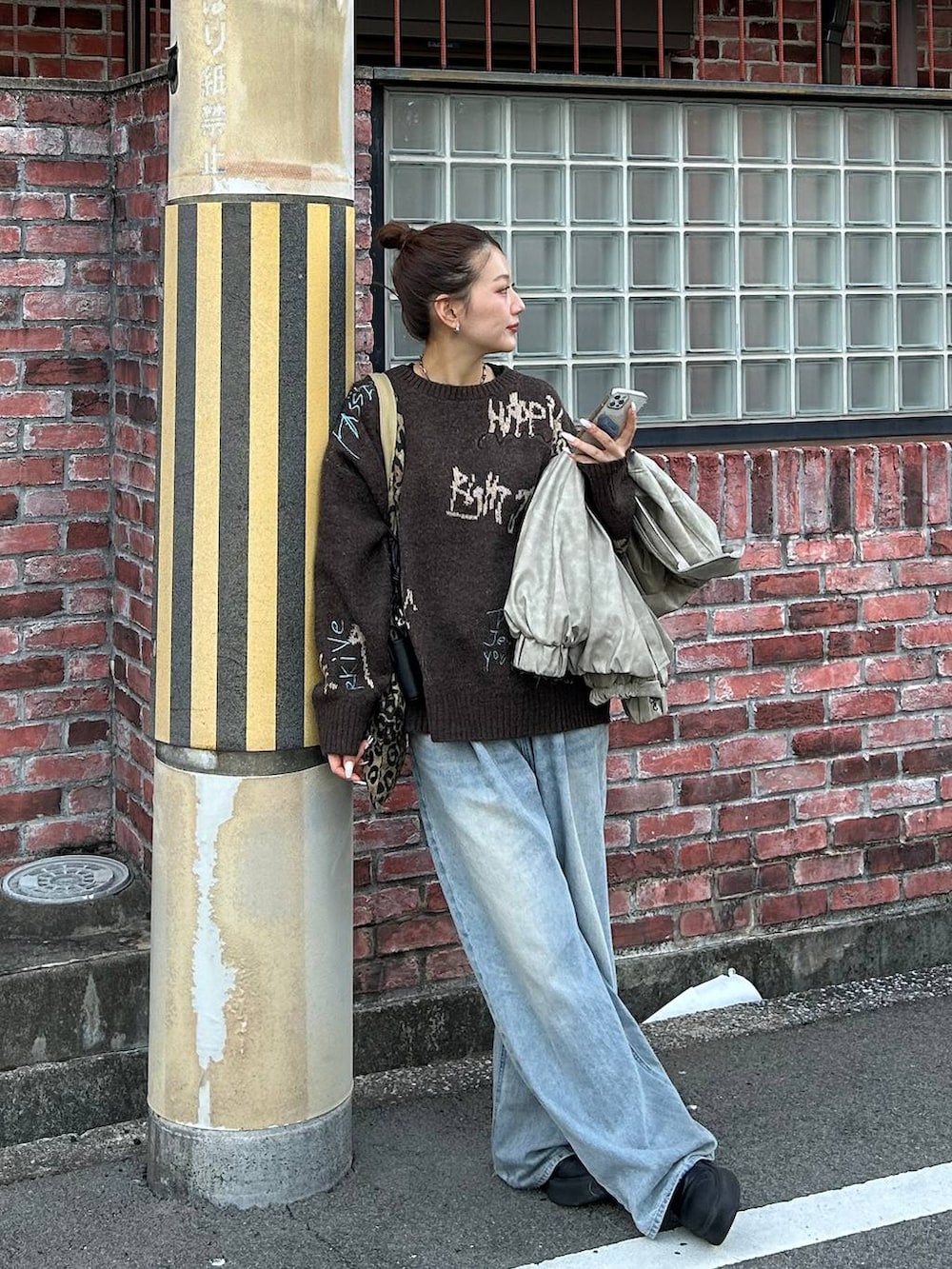 ブルー系のデニムパンツ、ベージュ系のトートバッグ、ブラウン系のニット/セーターを着用したレディースの冬コーディネートの6枚目の写真