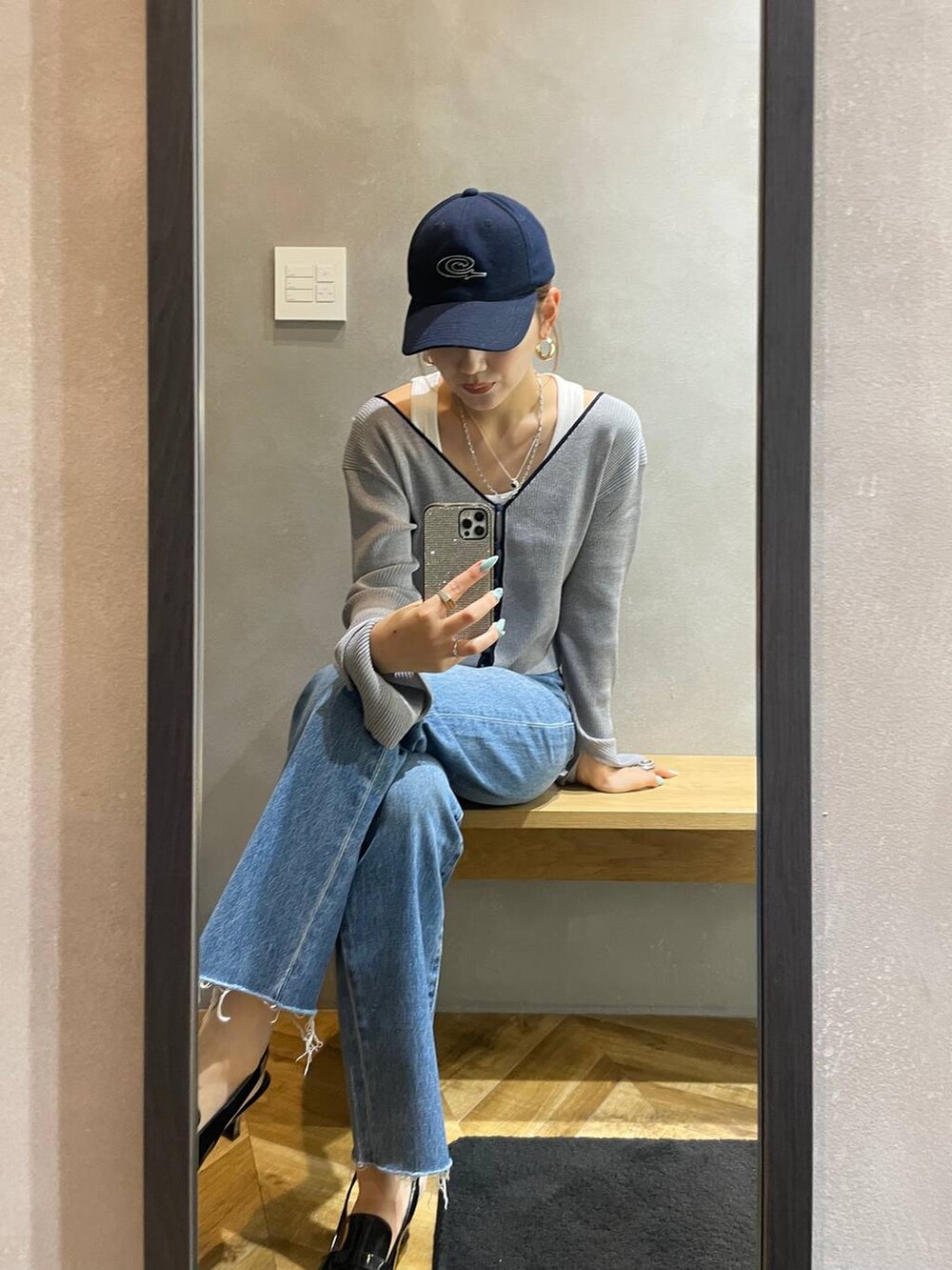 ブラック系のローファー、ブルー系のデニムパンツ、グレー系のカーディガン/ボレロを着用したレディースの秋コーディネートの2枚目の写真