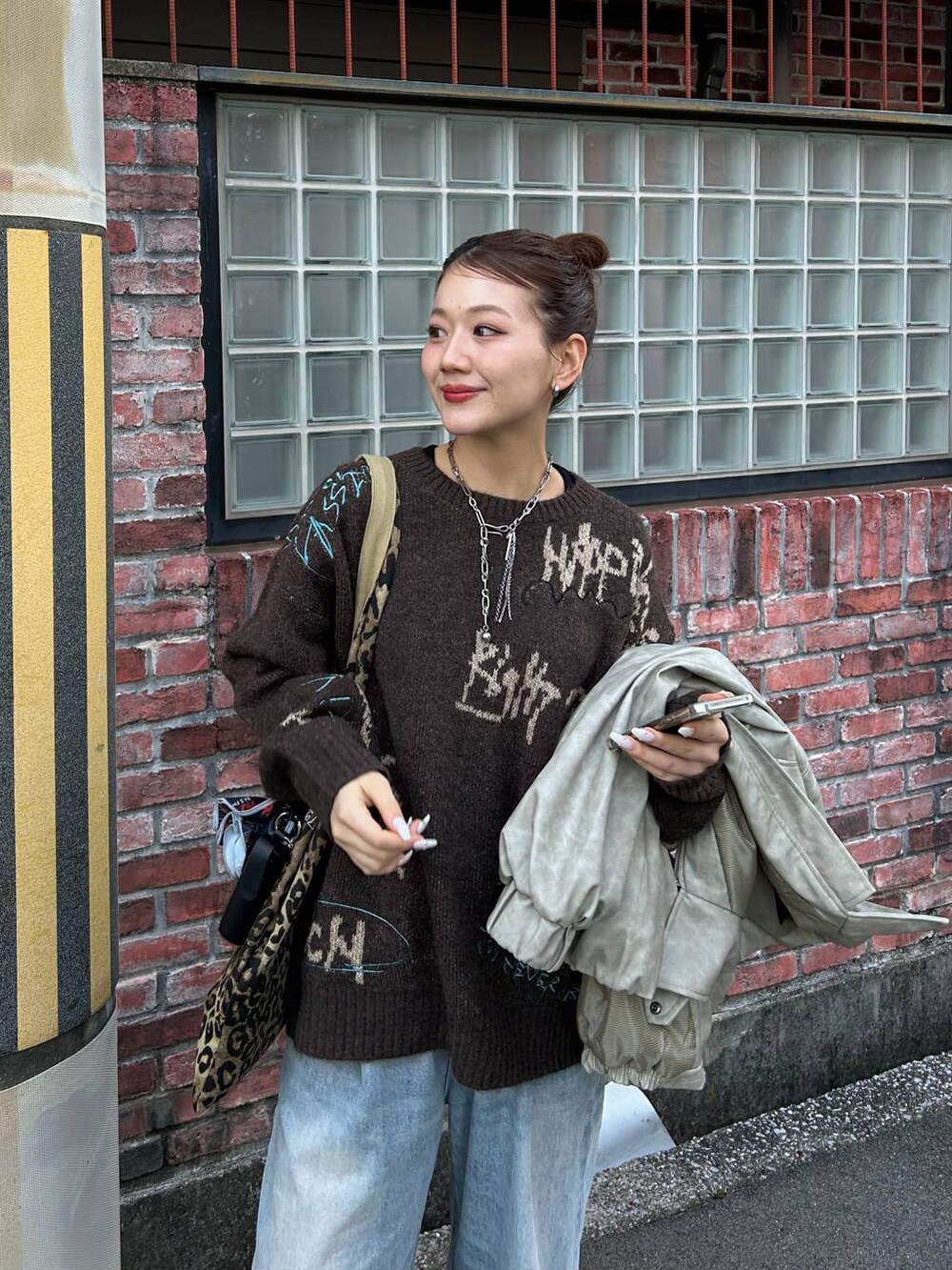 ブルー系のデニムパンツ、ベージュ系のトートバッグ、ブラウン系のニット/セーターを着用したレディースの冬コーディネートの3枚目の写真