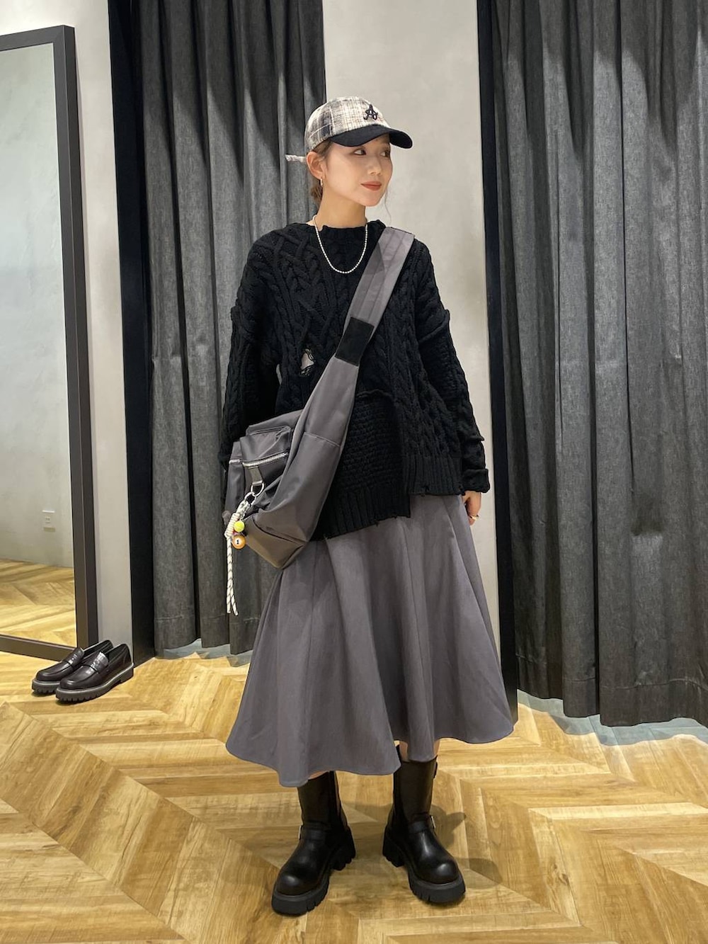 グレー系のショルダーバッグ、ブラック系のブーツ、ブラック系のニット/セーターを着用したレディースの秋コーディネートの7枚目の写真