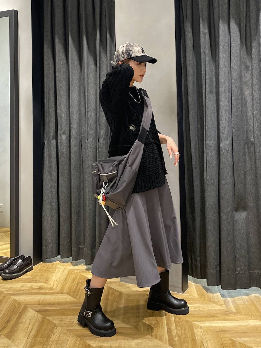 グレー系のショルダーバッグ、ブラック系のブーツ、ブラック系のニット/セーターを着用したレディースの秋コーディネートの4枚目の写真