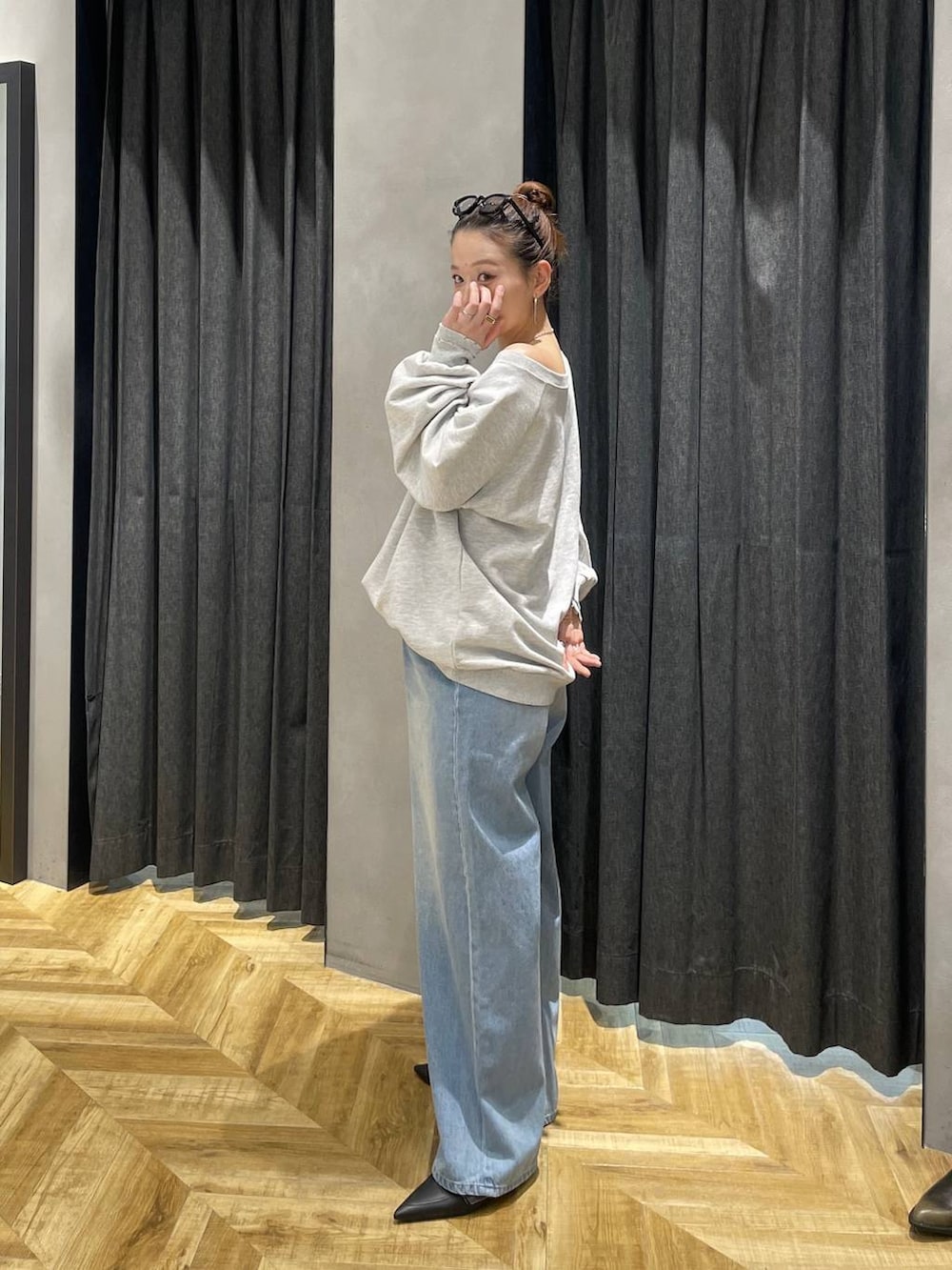 グレー系のスウェット、ブラック系のパンプス、ブルー系のデニムパンツを着用したレディースの冬コーディネートの4枚目の写真