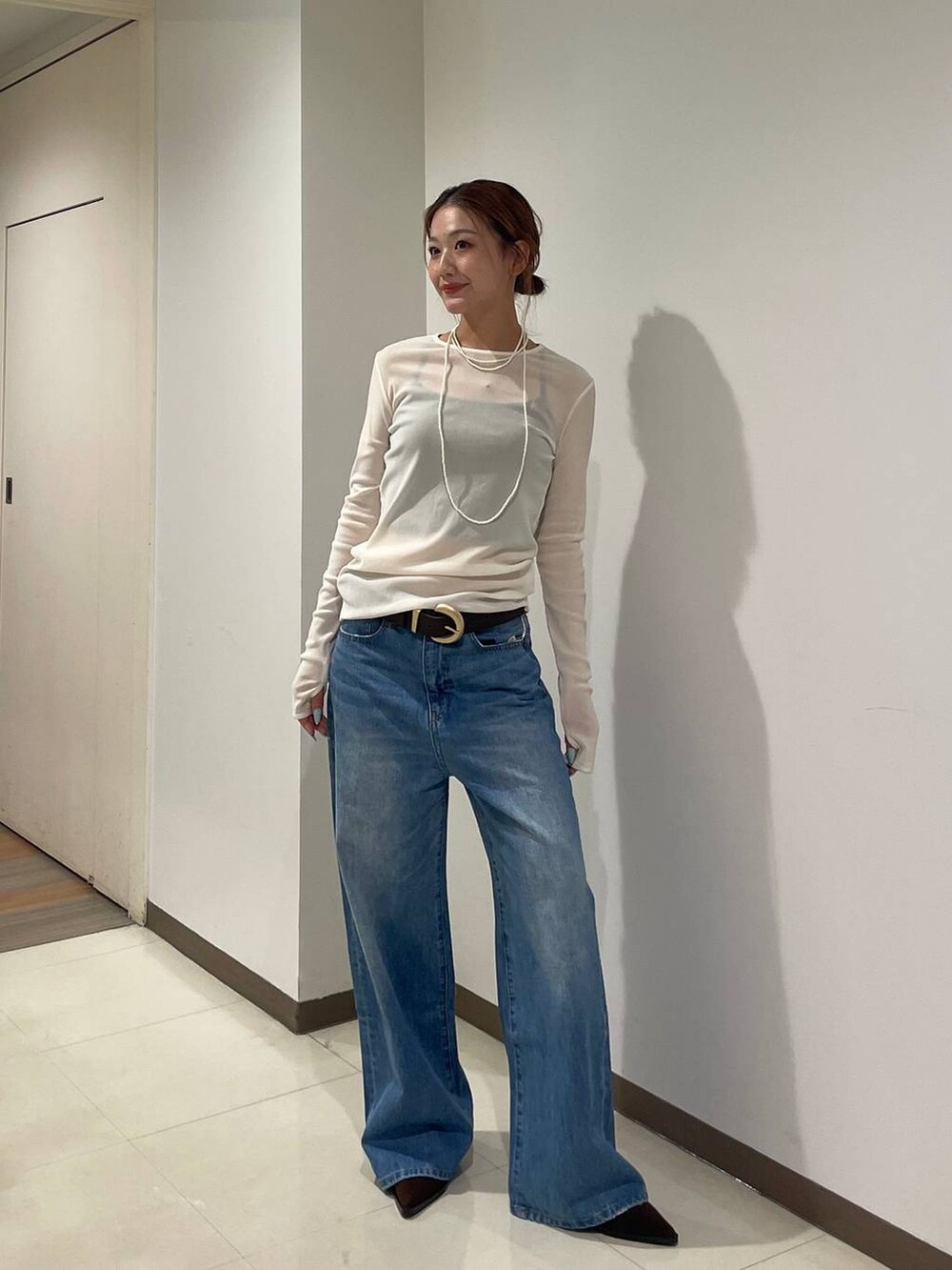 ホワイト系のTシャツ/カットソー、ブルー系のデニムパンツ、ブラック系のブーツを着用したレディースの秋コーディネートの4枚目の写真