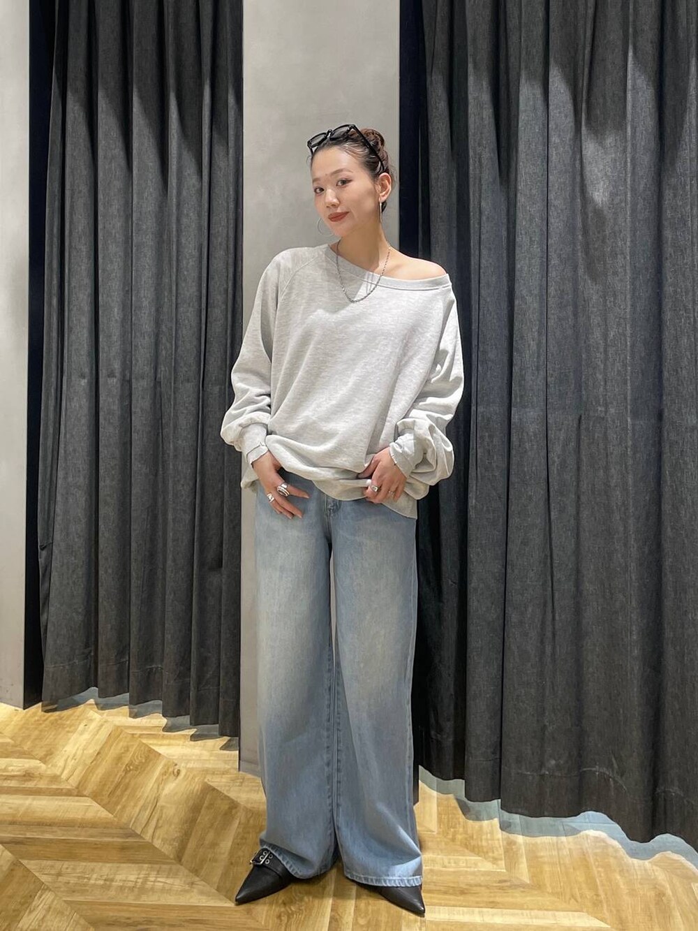 グレー系のスウェット、ブラック系のパンプス、ブルー系のデニムパンツを着用したレディースの冬コーディネートの2枚目の写真