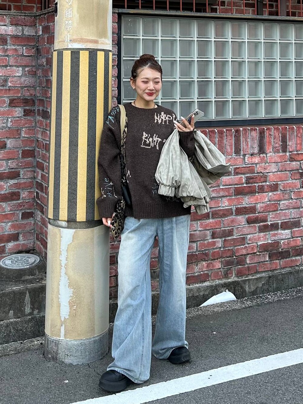 ブルー系のデニムパンツ、ベージュ系のトートバッグ、ブラウン系のニット/セーターを着用したレディースの冬コーディネートの5枚目の写真