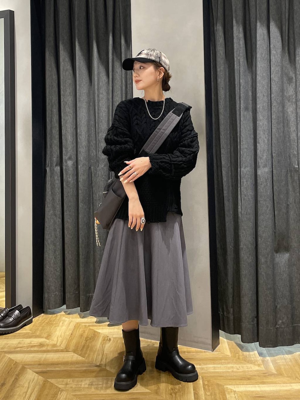 グレー系のショルダーバッグ、ブラック系のブーツ、ブラック系のニット/セーターを着用したレディースの秋コーディネートの5枚目の写真
