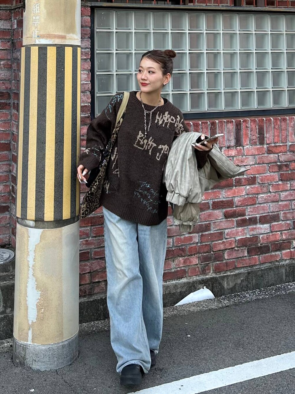 ブルー系のデニムパンツ、ベージュ系のトートバッグ、ブラウン系のニット/セーターを着用したレディースの冬コーディネートの2枚目の写真