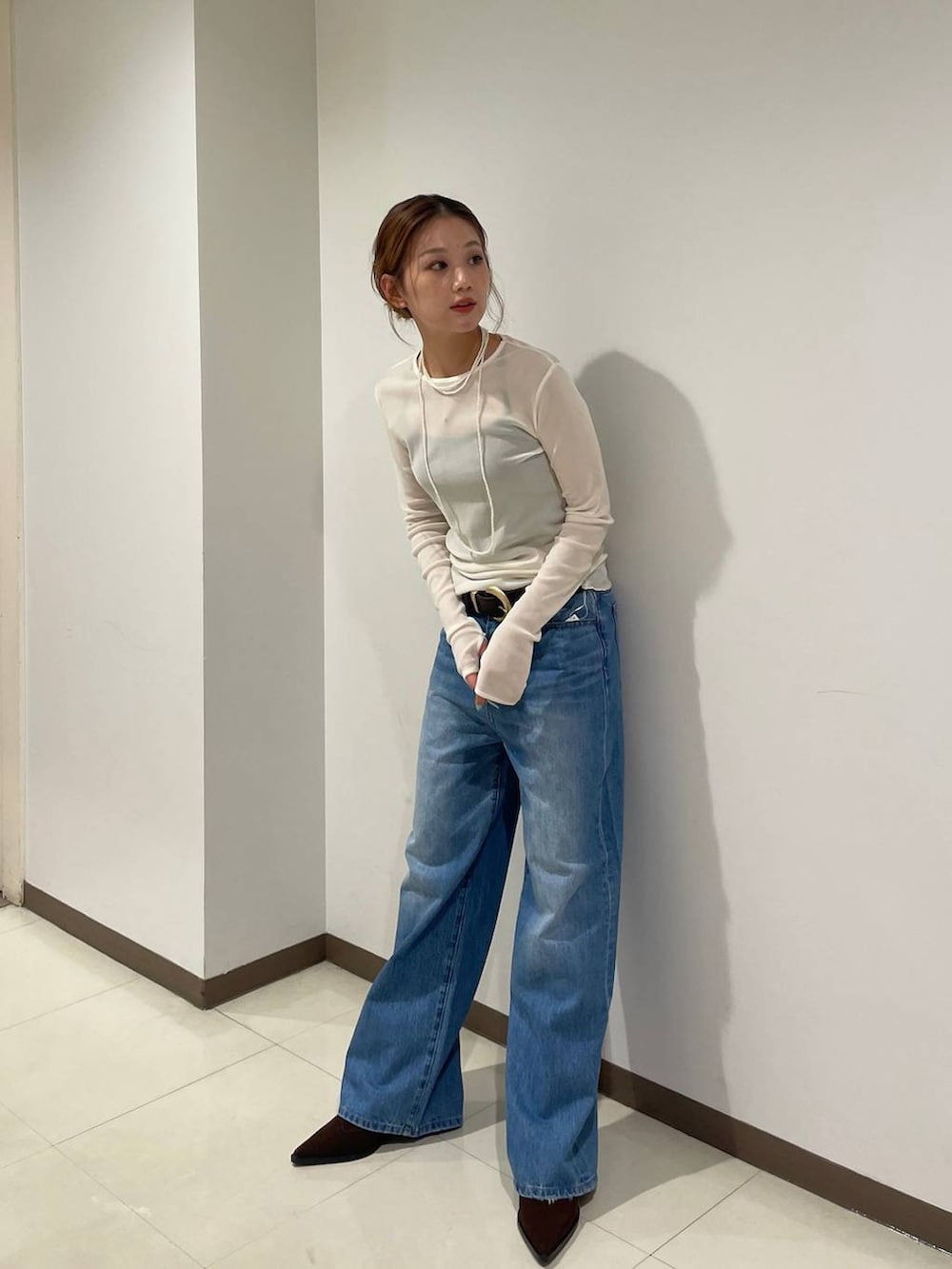 ホワイト系のTシャツ/カットソー、ブルー系のデニムパンツ、ブラック系のブーツを着用したレディースの秋コーディネートの3枚目の写真