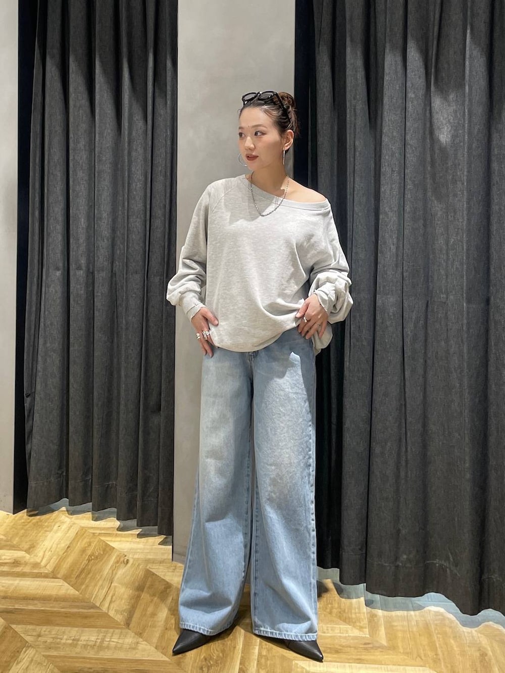 グレー系のスウェット、ブラック系のパンプス、ブルー系のデニムパンツを着用したレディースの冬コーディネートの6枚目の写真