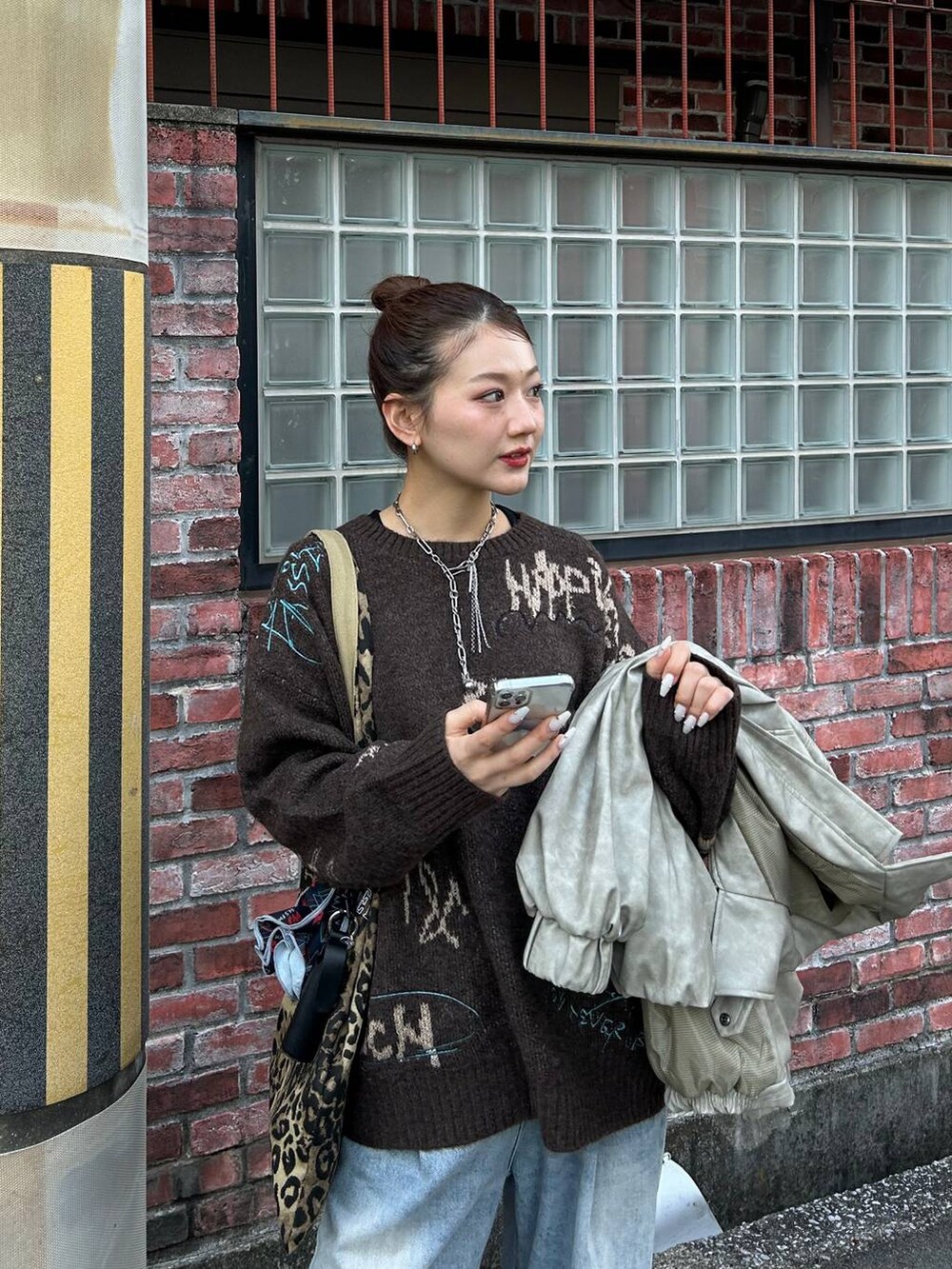 ブルー系のデニムパンツ、ベージュ系のトートバッグ、ブラウン系のニット/セーターを着用したレディースの冬コーディネートの4枚目の写真