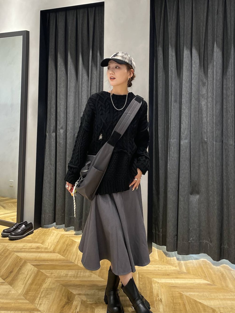グレー系のショルダーバッグ、ブラック系のブーツ、ブラック系のニット/セーターを着用したレディースの秋コーディネートの6枚目の写真