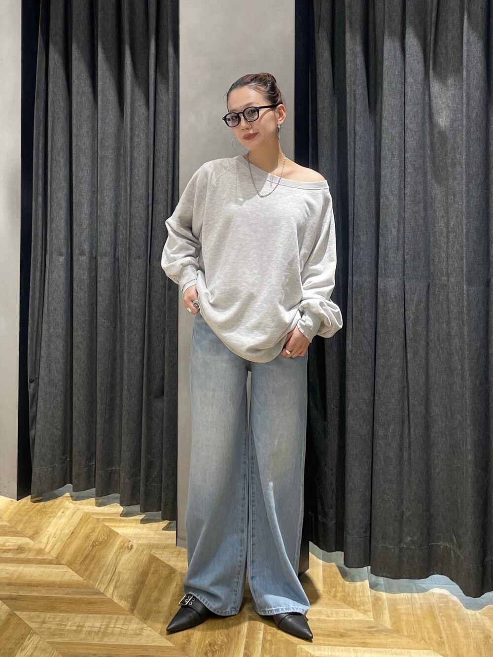 グレー系のスウェット、ブラック系のパンプス、ブルー系のデニムパンツを着用したレディースの冬コーディネートの5枚目の写真