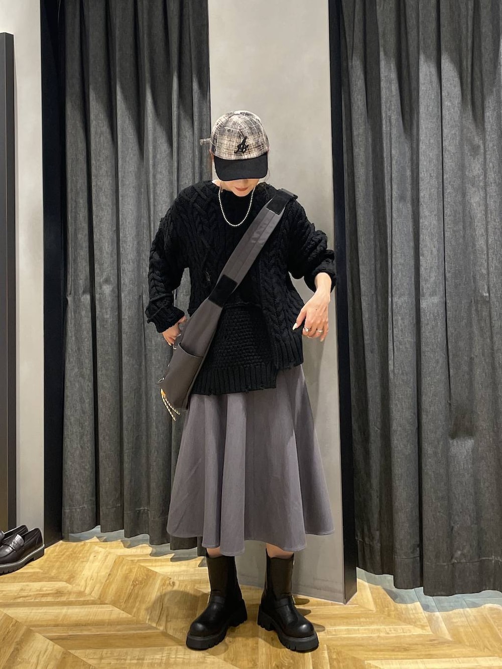 グレー系のショルダーバッグ、ブラック系のブーツ、ブラック系のニット/セーターを着用したレディースの秋コーディネートの3枚目の写真